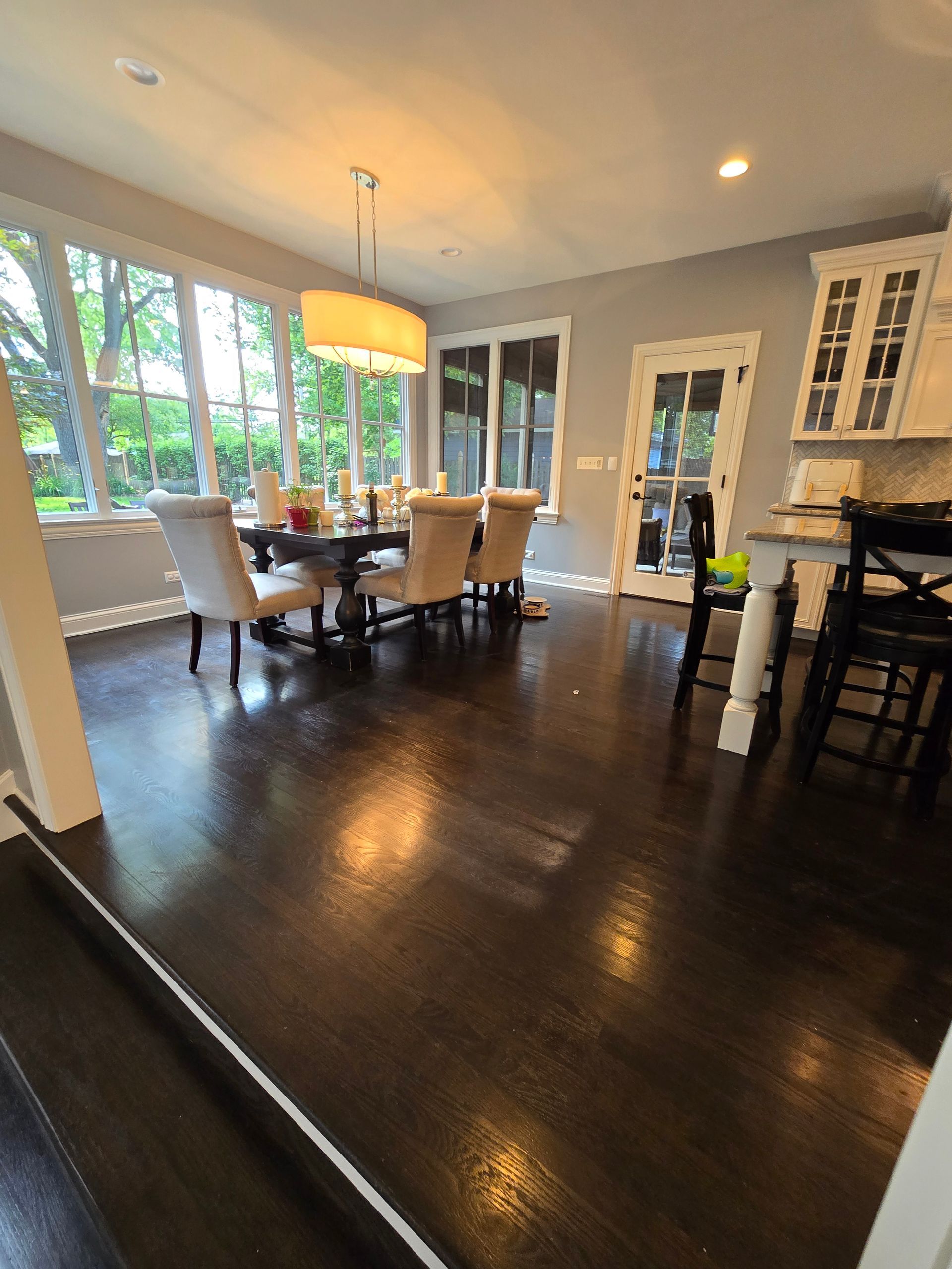 A dining room with a table and chairs and a lot of windows.