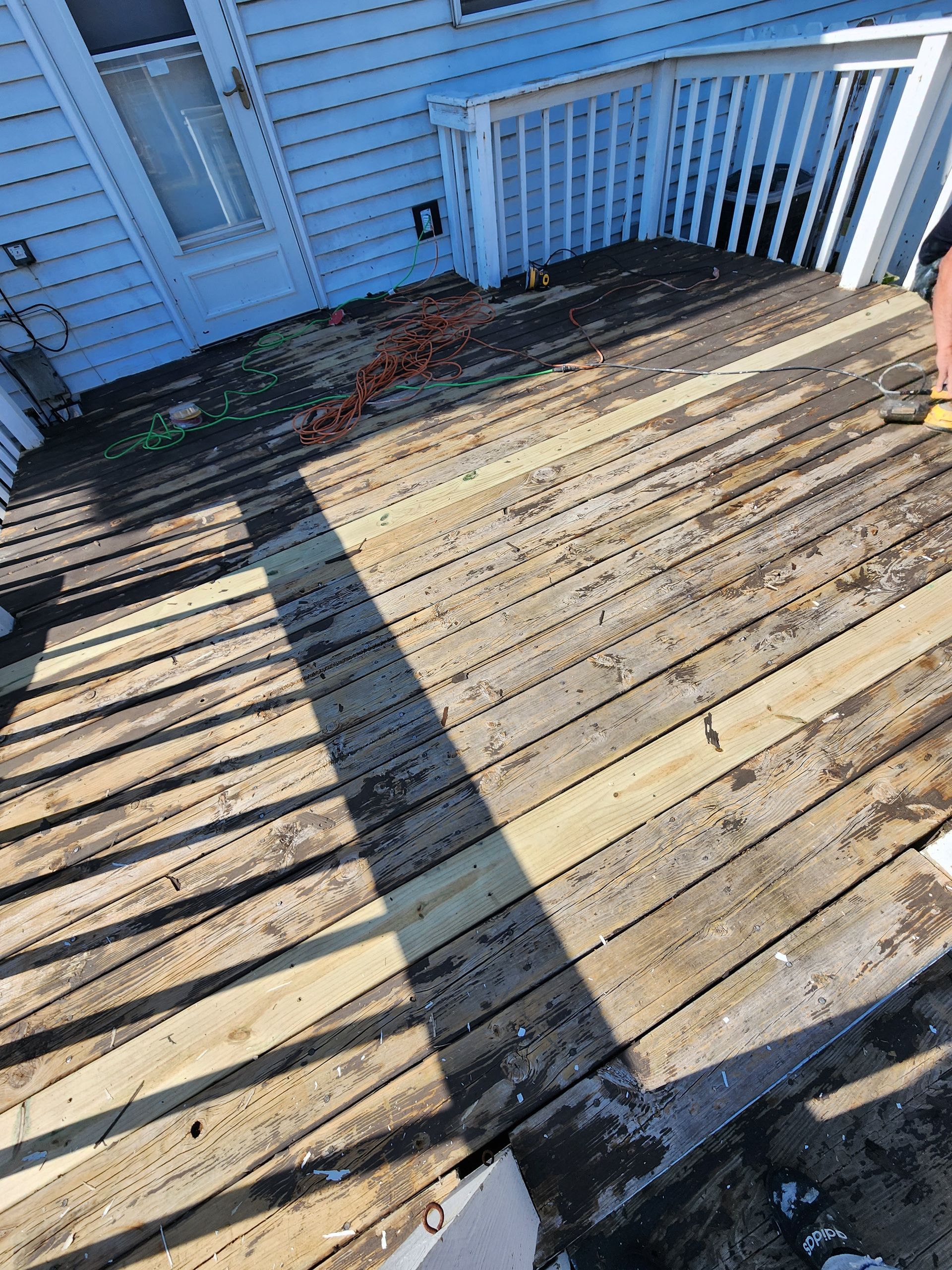 A person is standing on a wooden deck next to a house.
