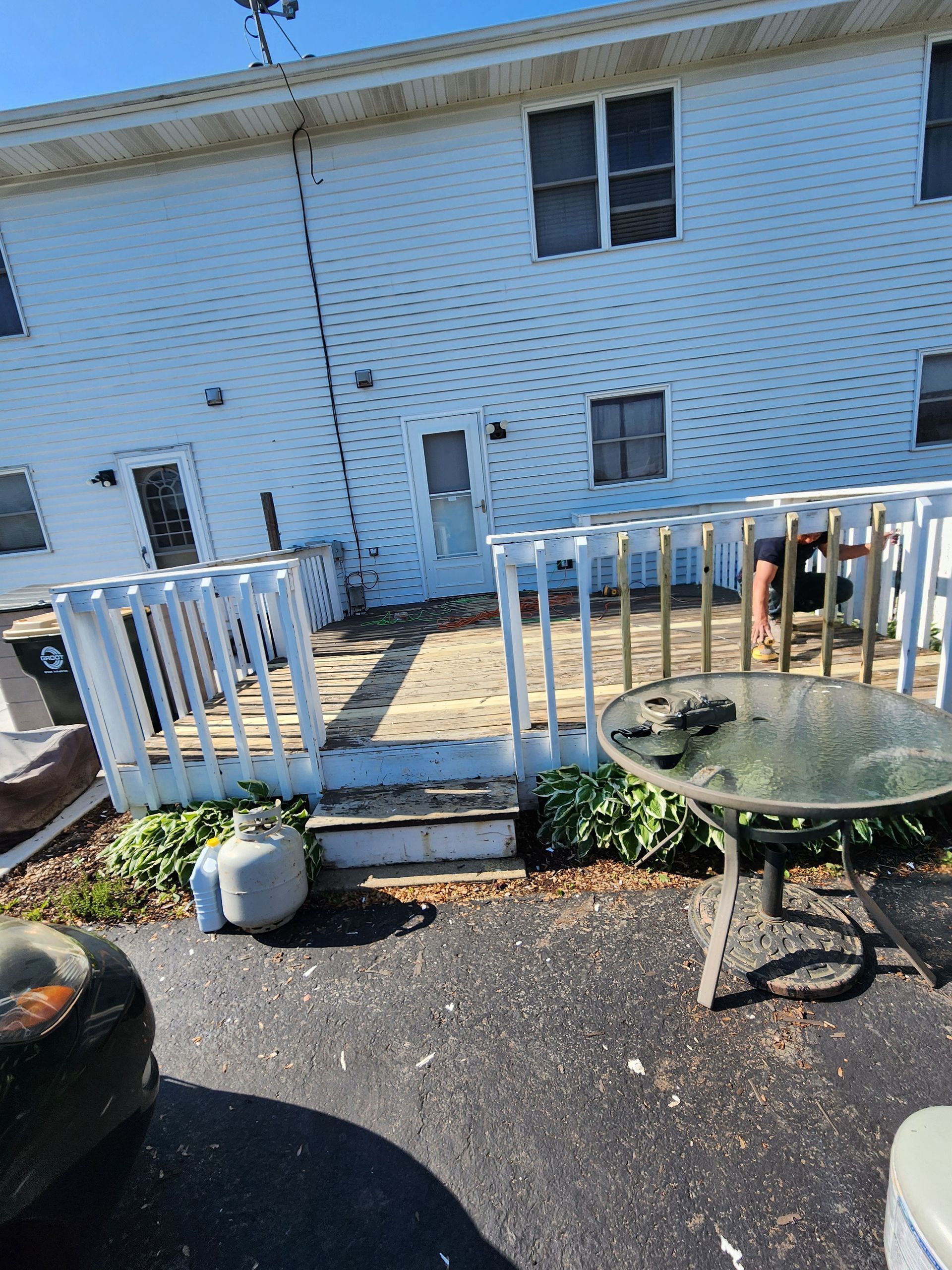 A white house with a deck and a table in front of it.