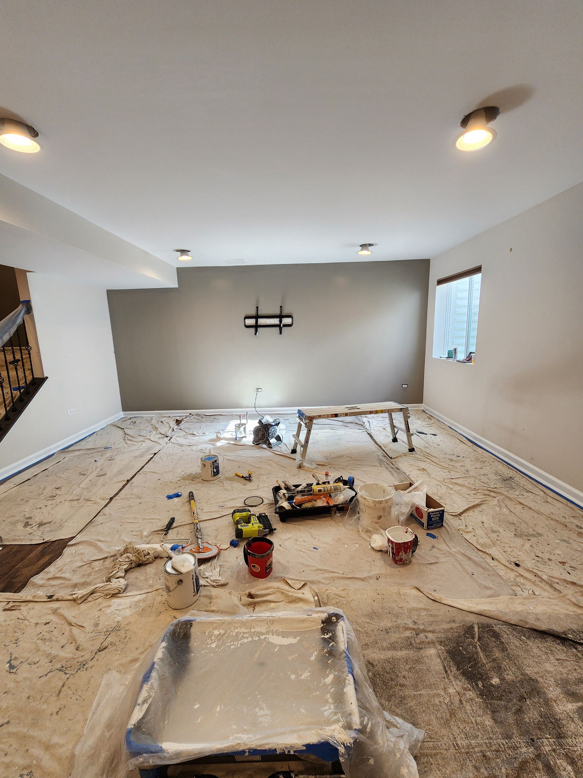 A room that is being painted with a lot of paint on the floor.