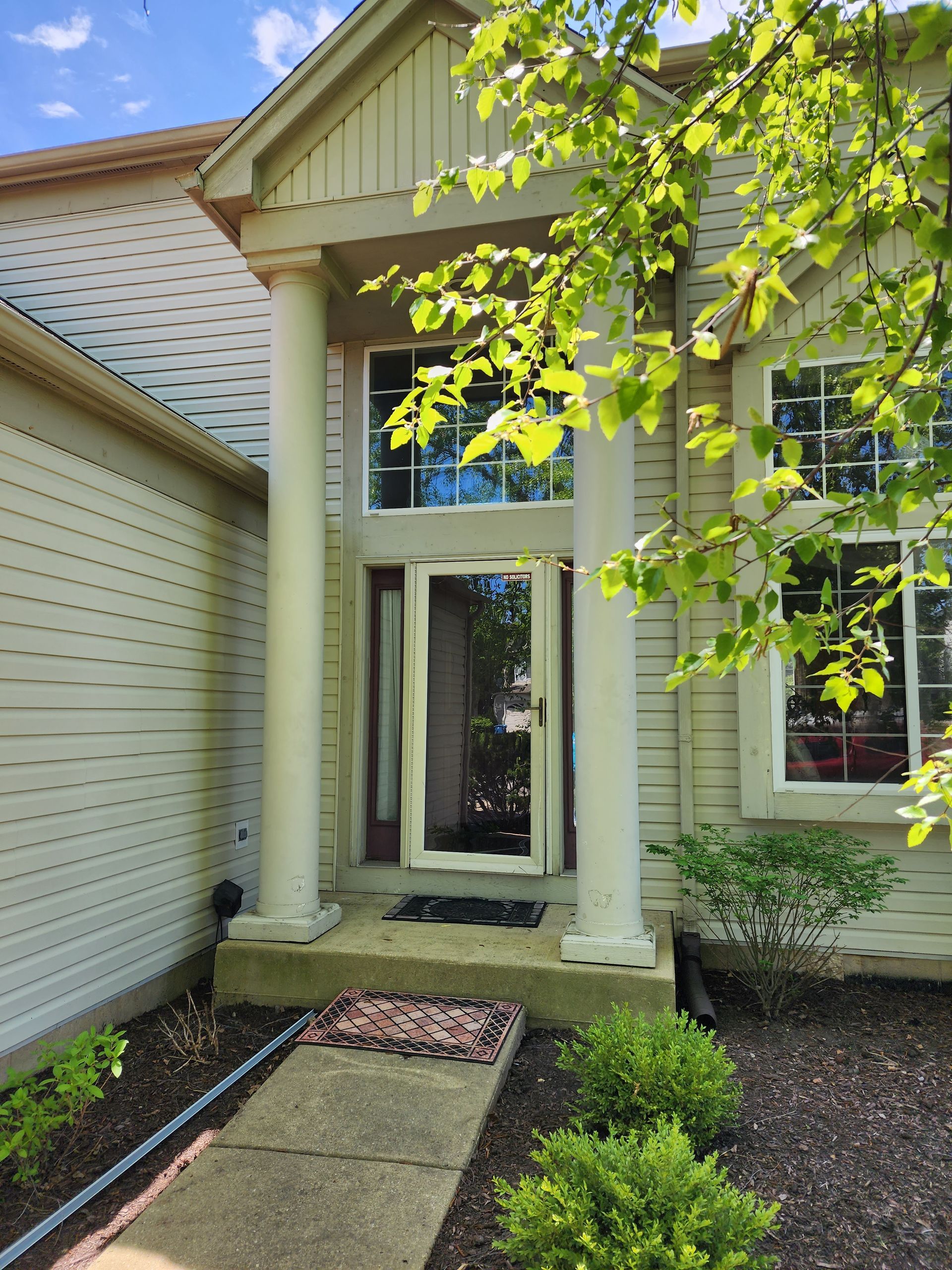The front door of a house with columns and a sliding glass door
