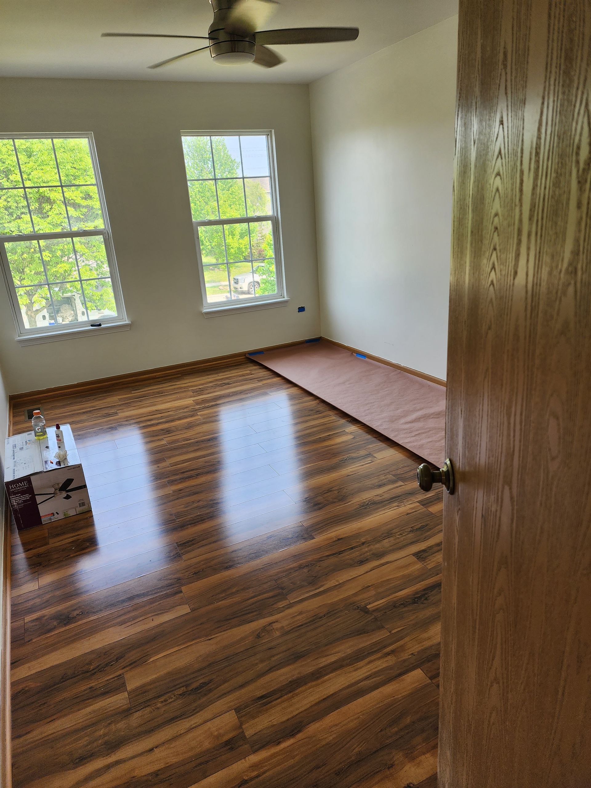 An empty room with hardwood floors and a ceiling fan.