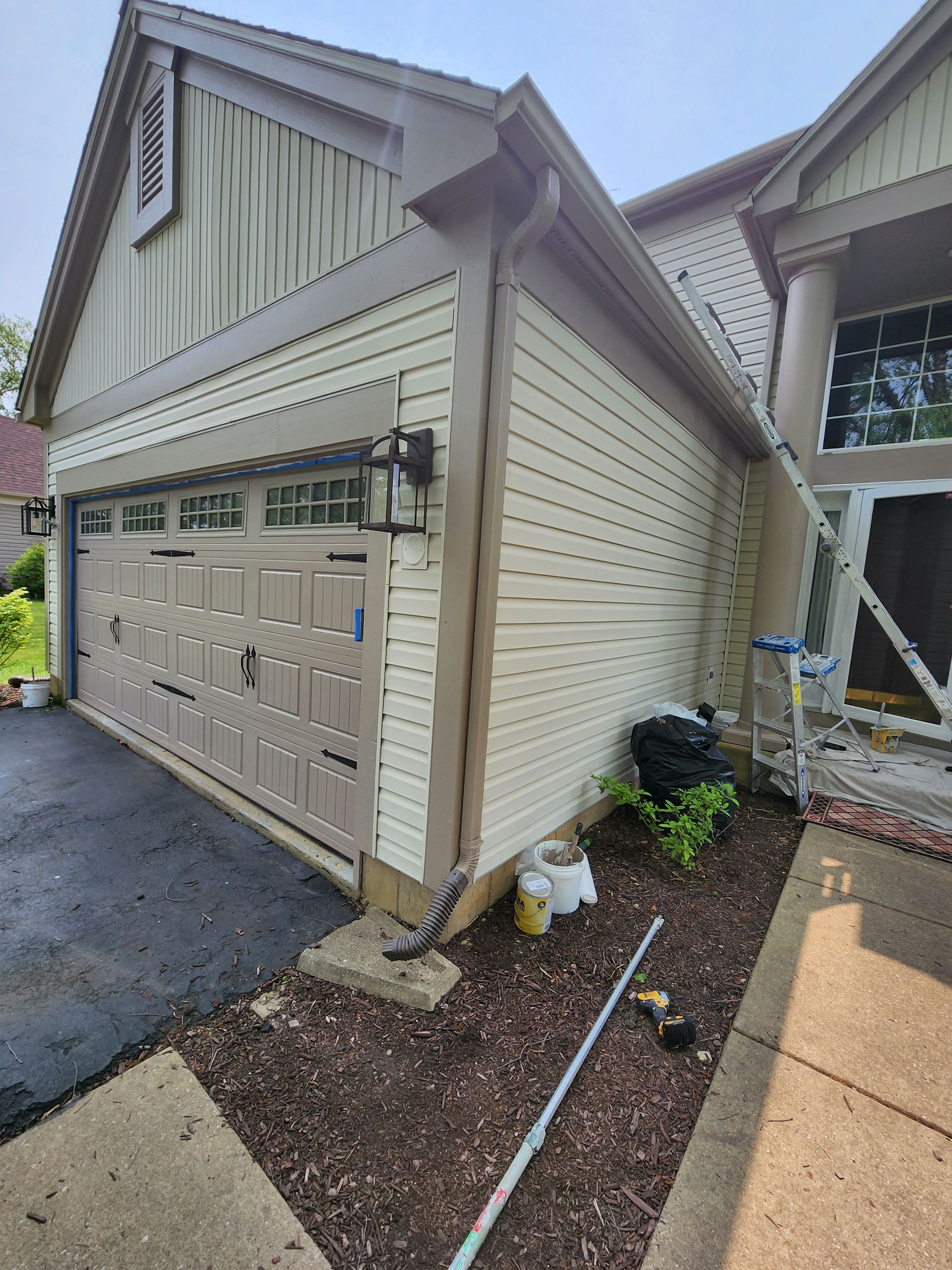 A garage door is being painted on the side of a house.