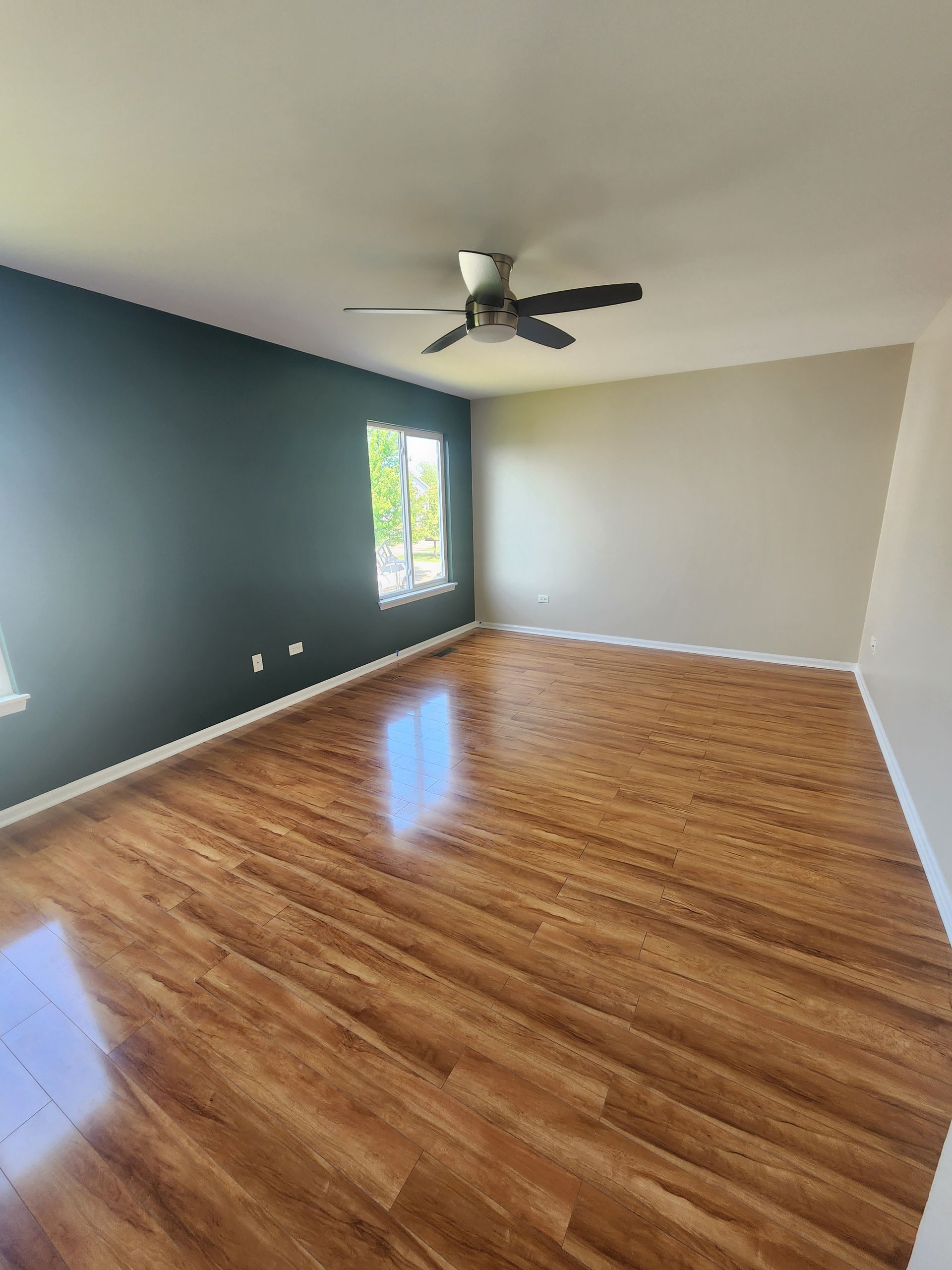 An empty living room with hardwood floors and a ceiling fan.