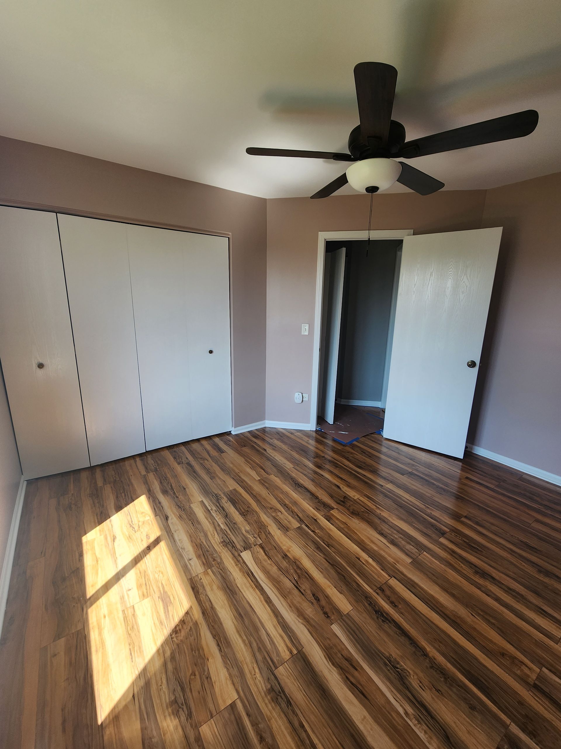 An empty bedroom with hardwood floors and a ceiling fan.