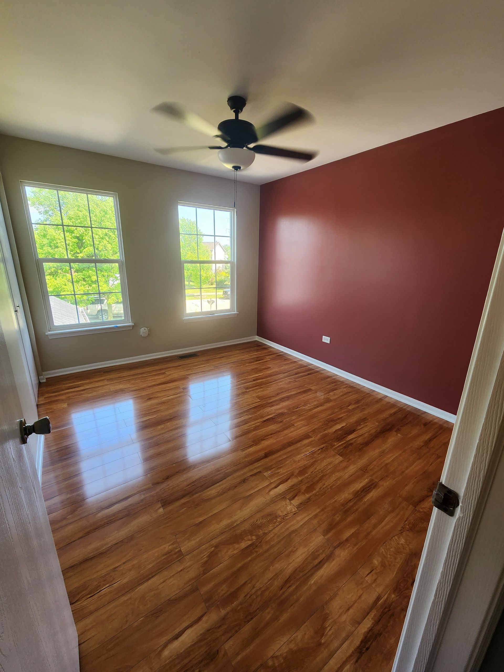 An empty bedroom with hardwood floors and a ceiling fan.
