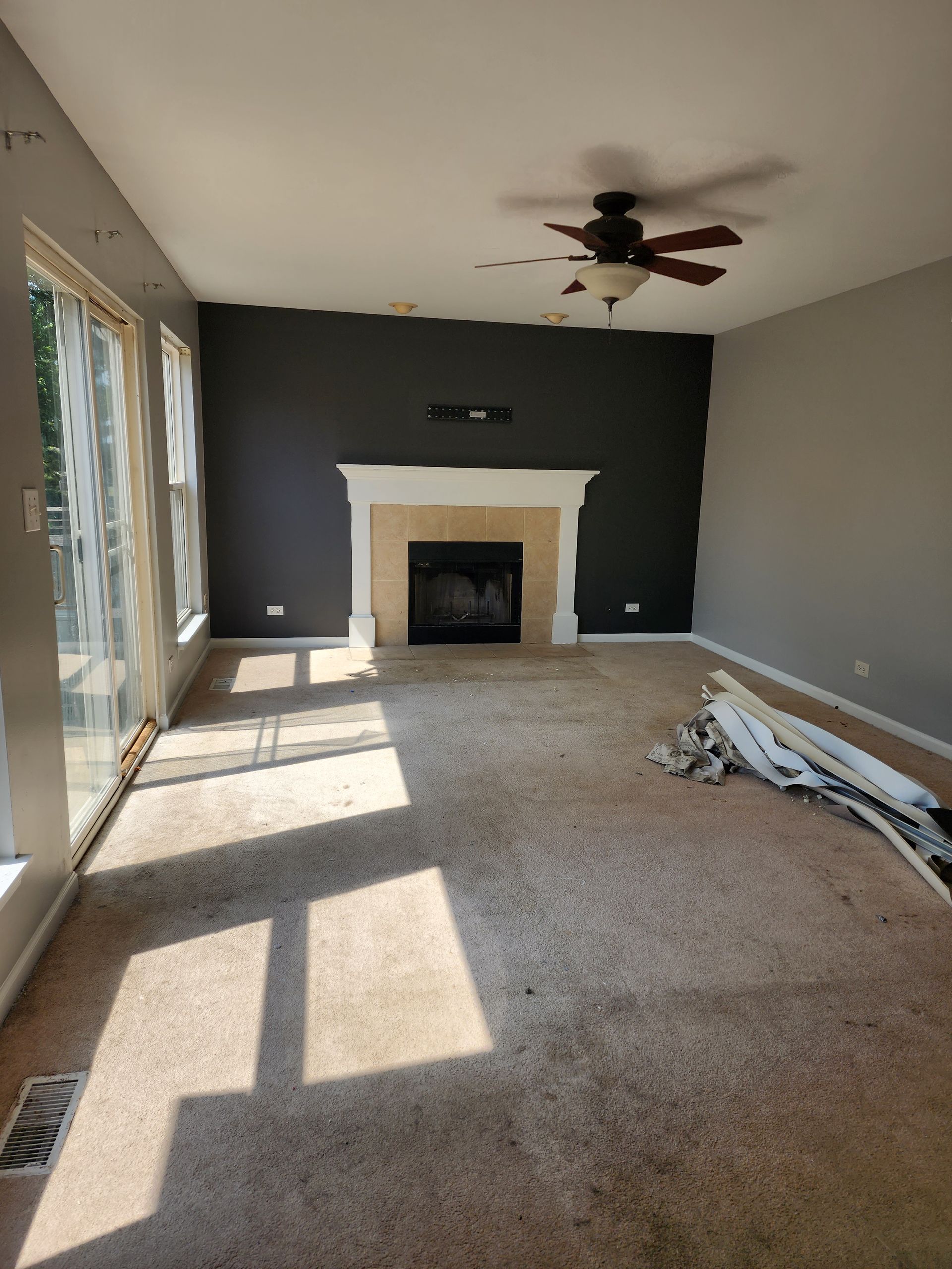 An empty living room with a fireplace and a ceiling fan.