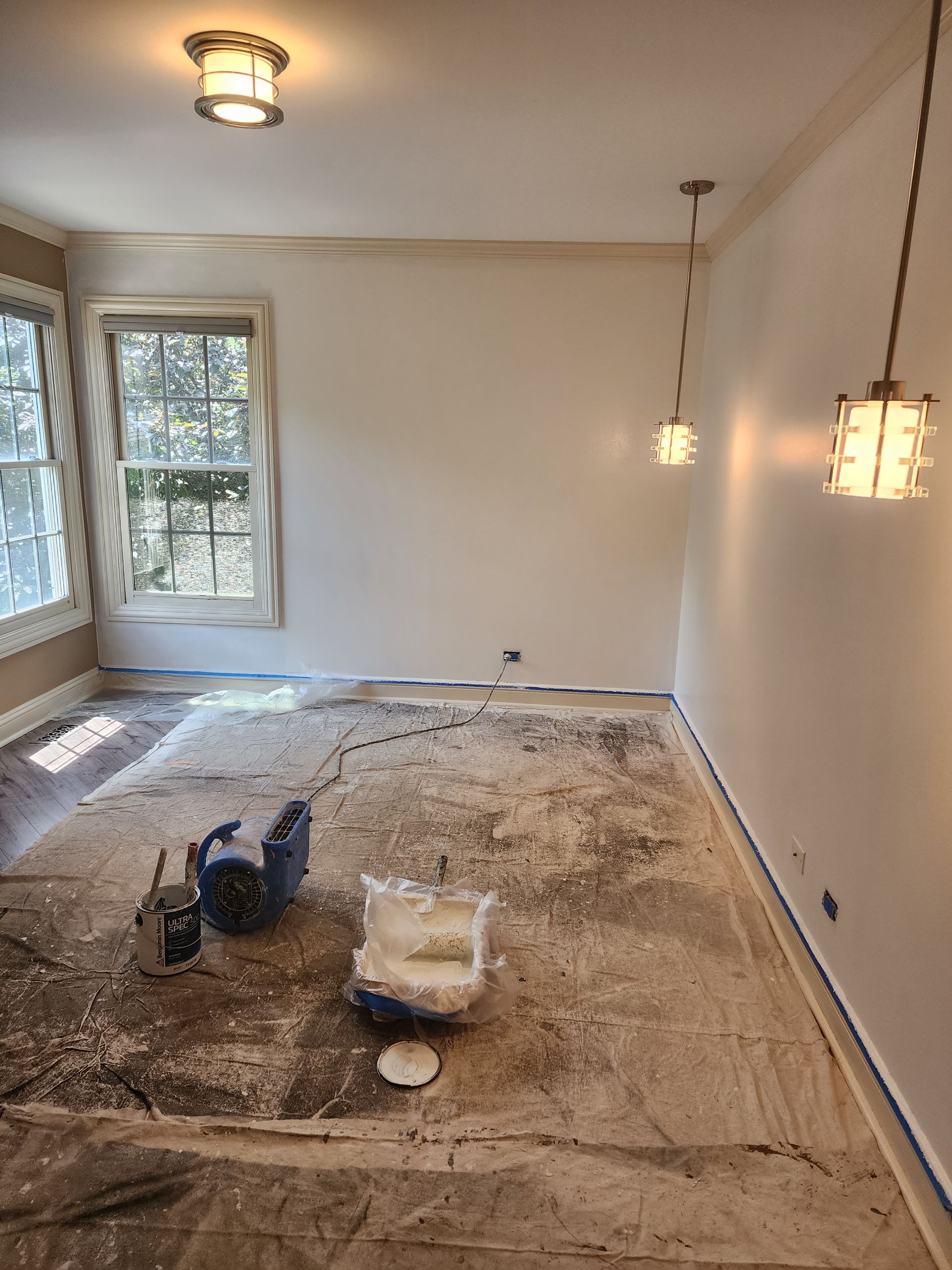 A room with white walls and a blue bag of paint on the floor.