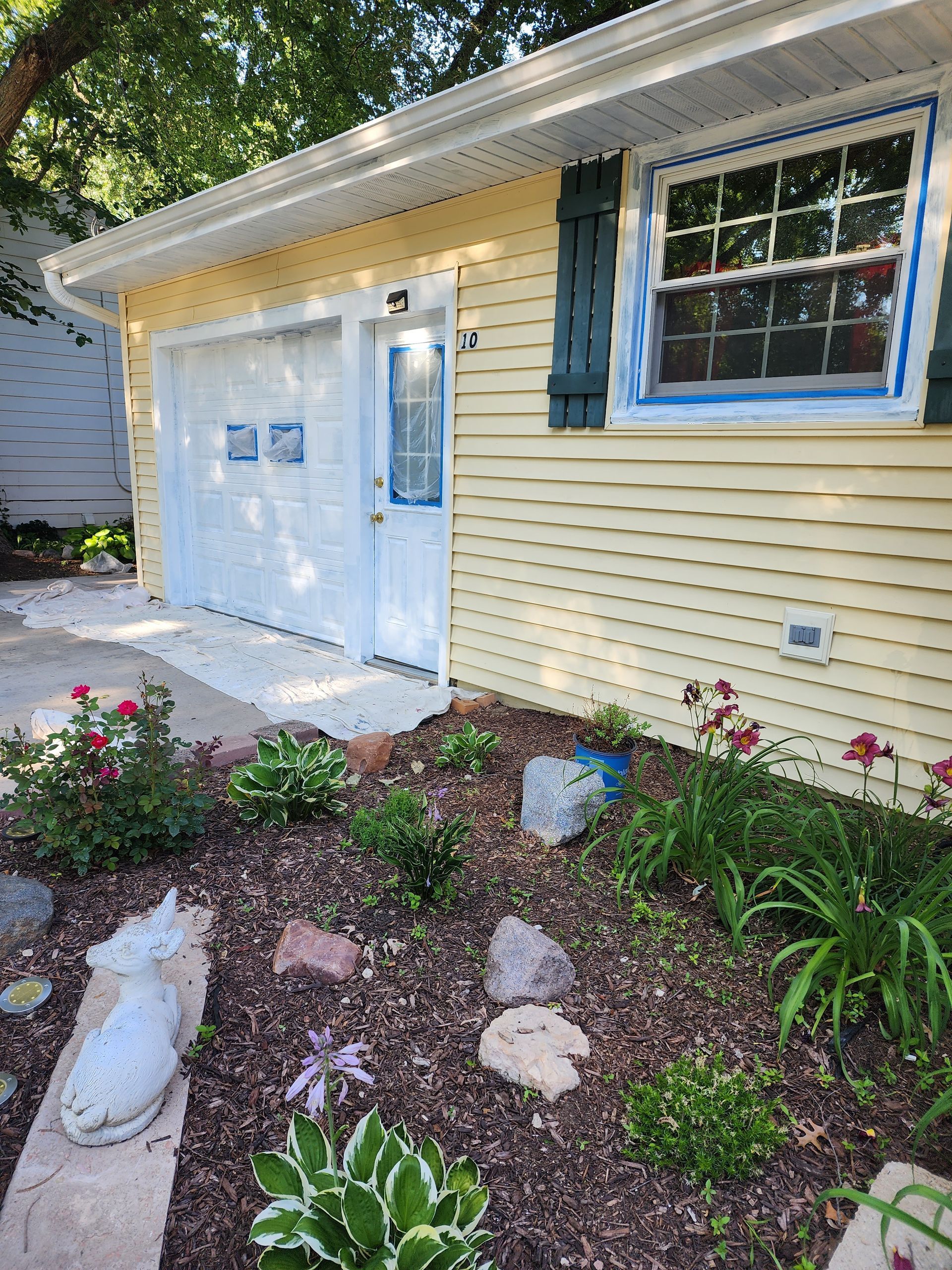 A yellow house with a white garage door and a window.