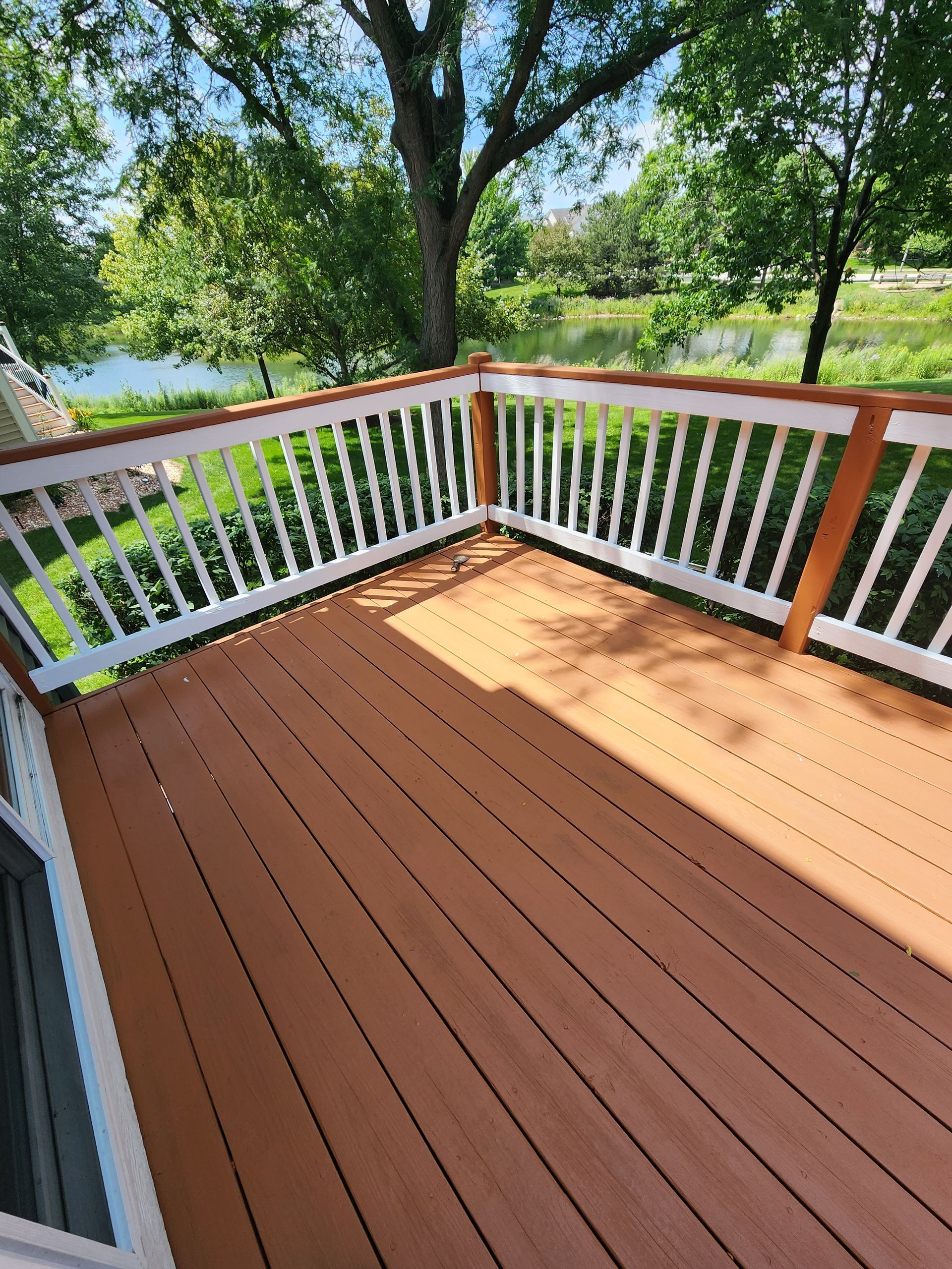 A wooden deck with a white railing and a view of a lake.
