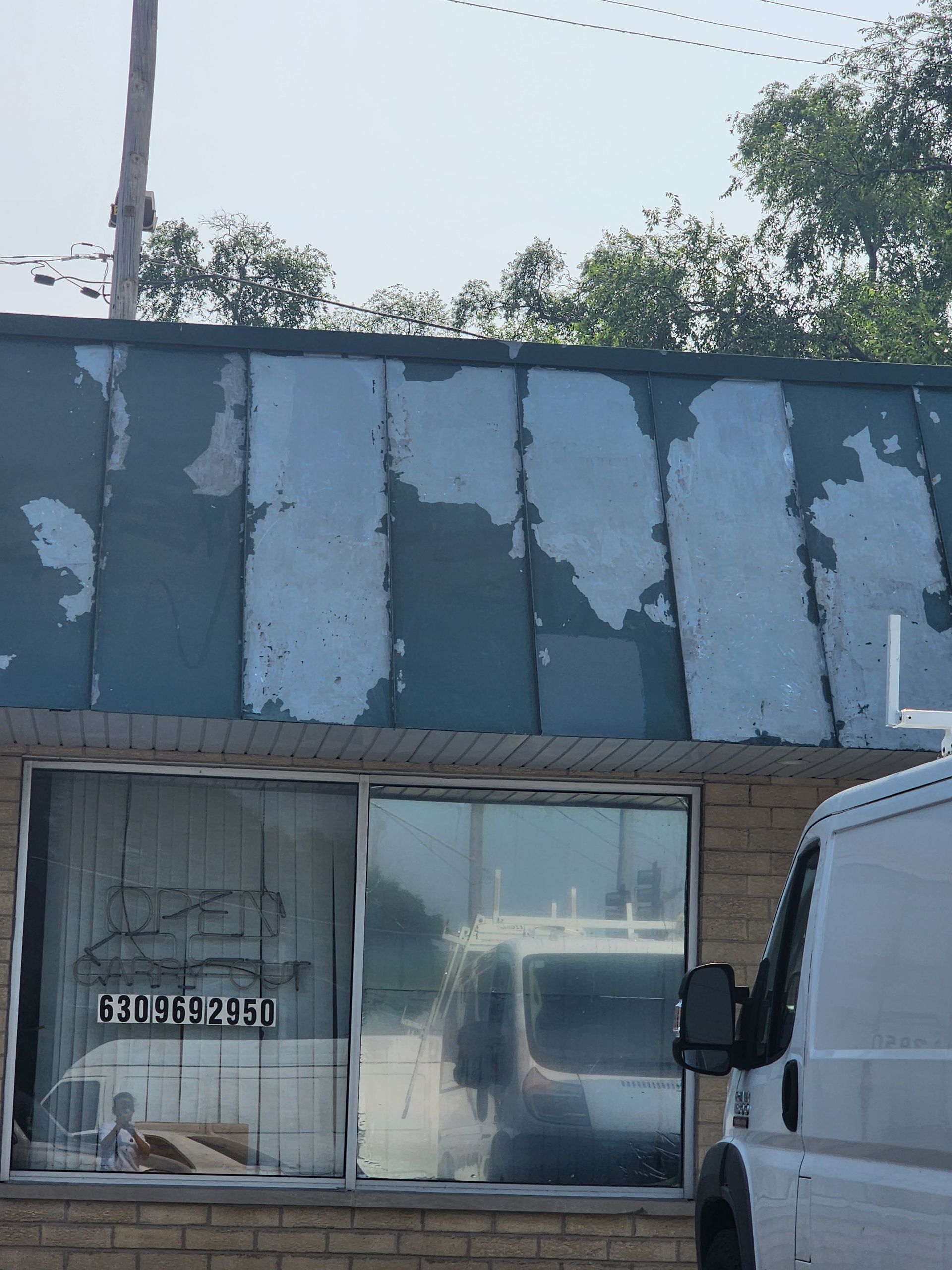 A white van is parked in front of a brick building