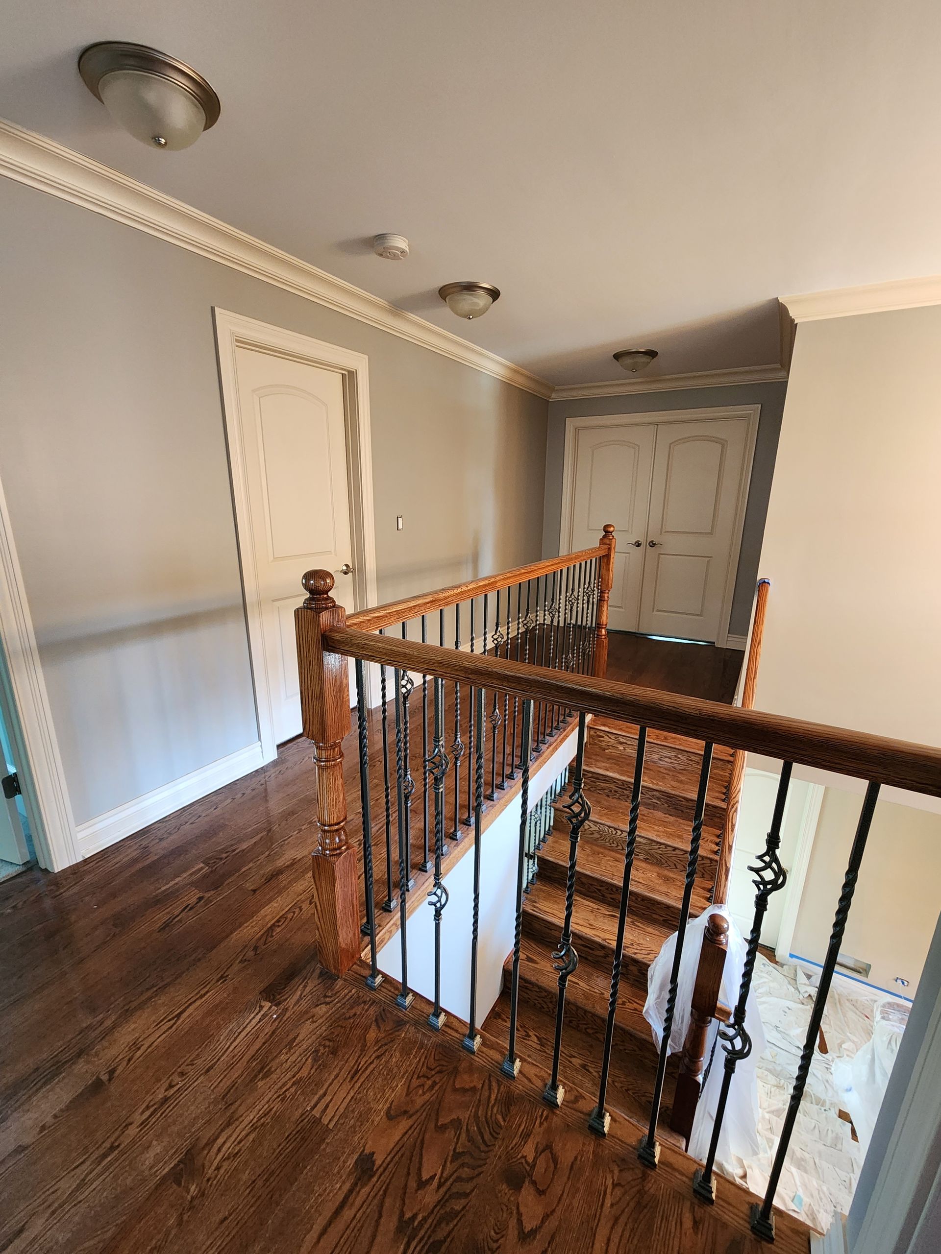 A hallway with stairs and a wooden railing in a house.