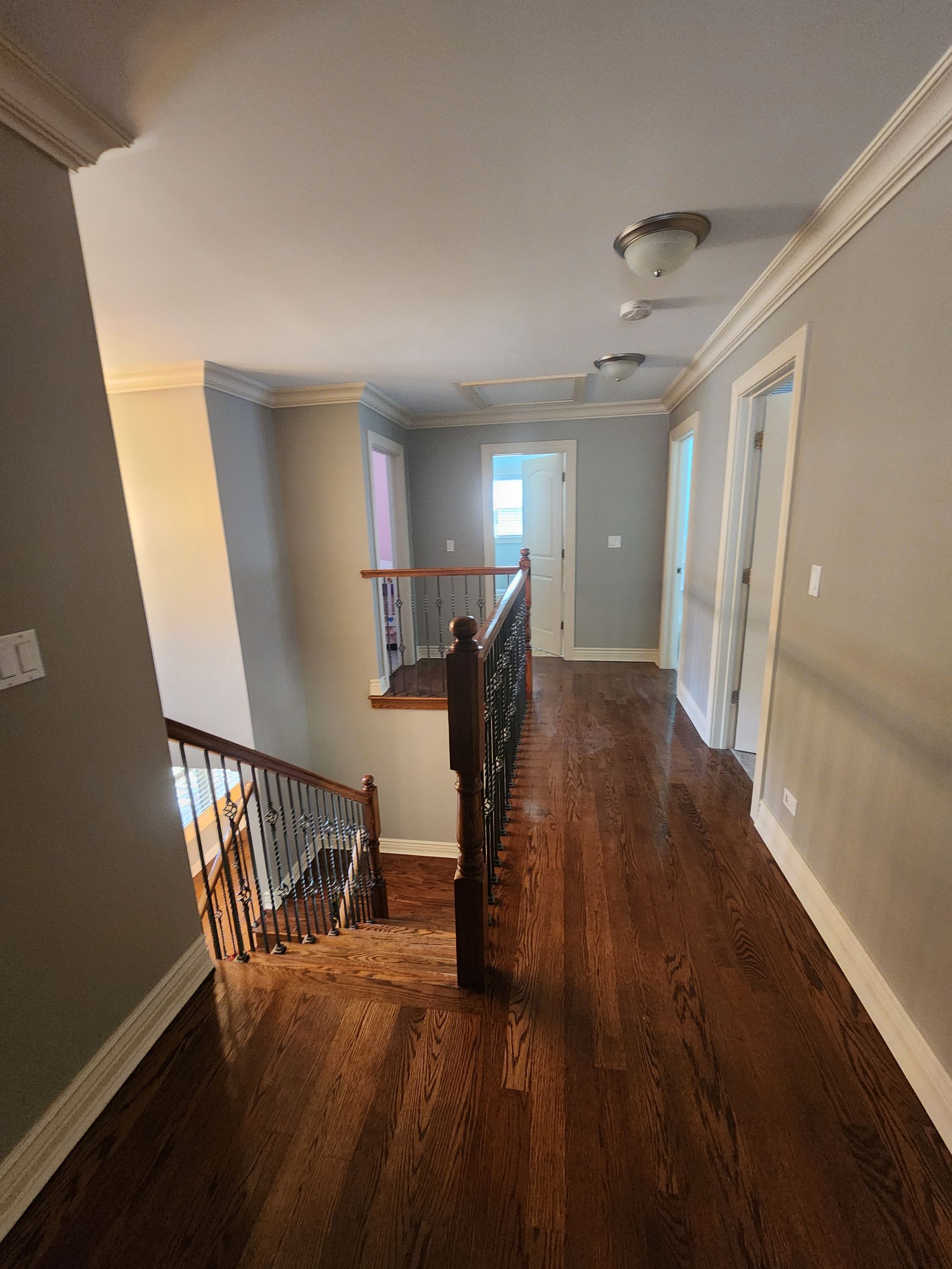 A hallway with wooden floors and stairs in a house.