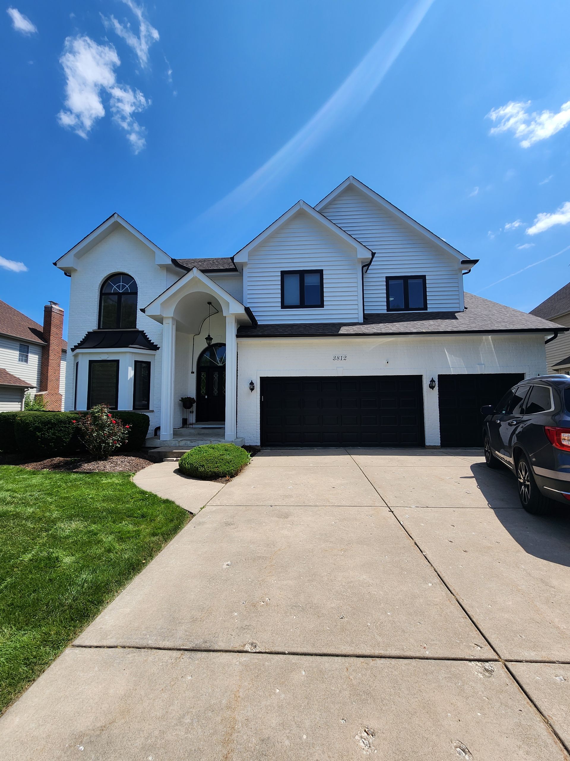 A white house with black garage doors and a car parked in front of it
