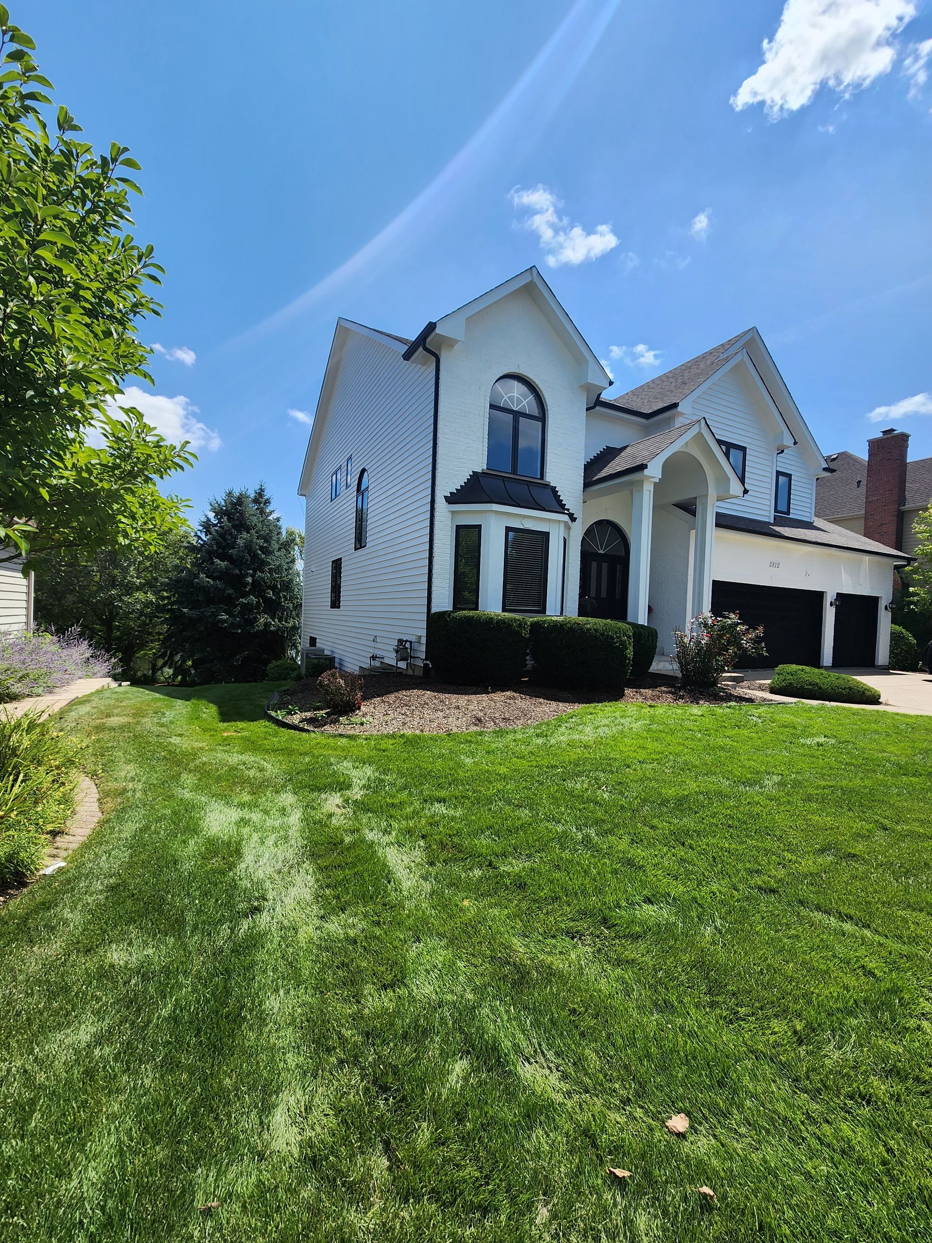 A large white house with a lush green lawn in front of it.