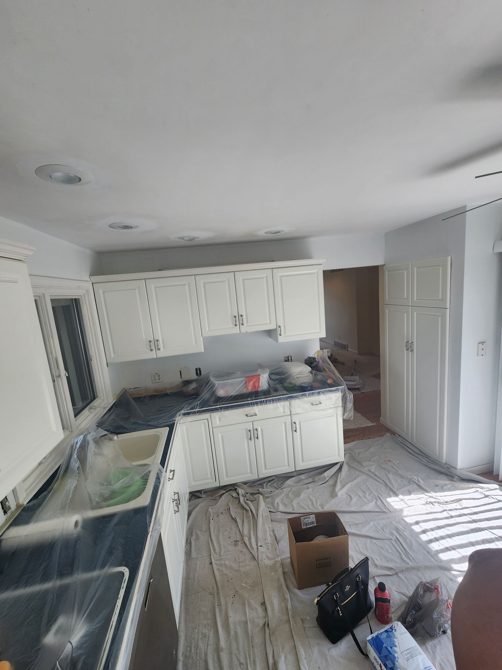 A kitchen with white cabinets and black counter tops is being painted.