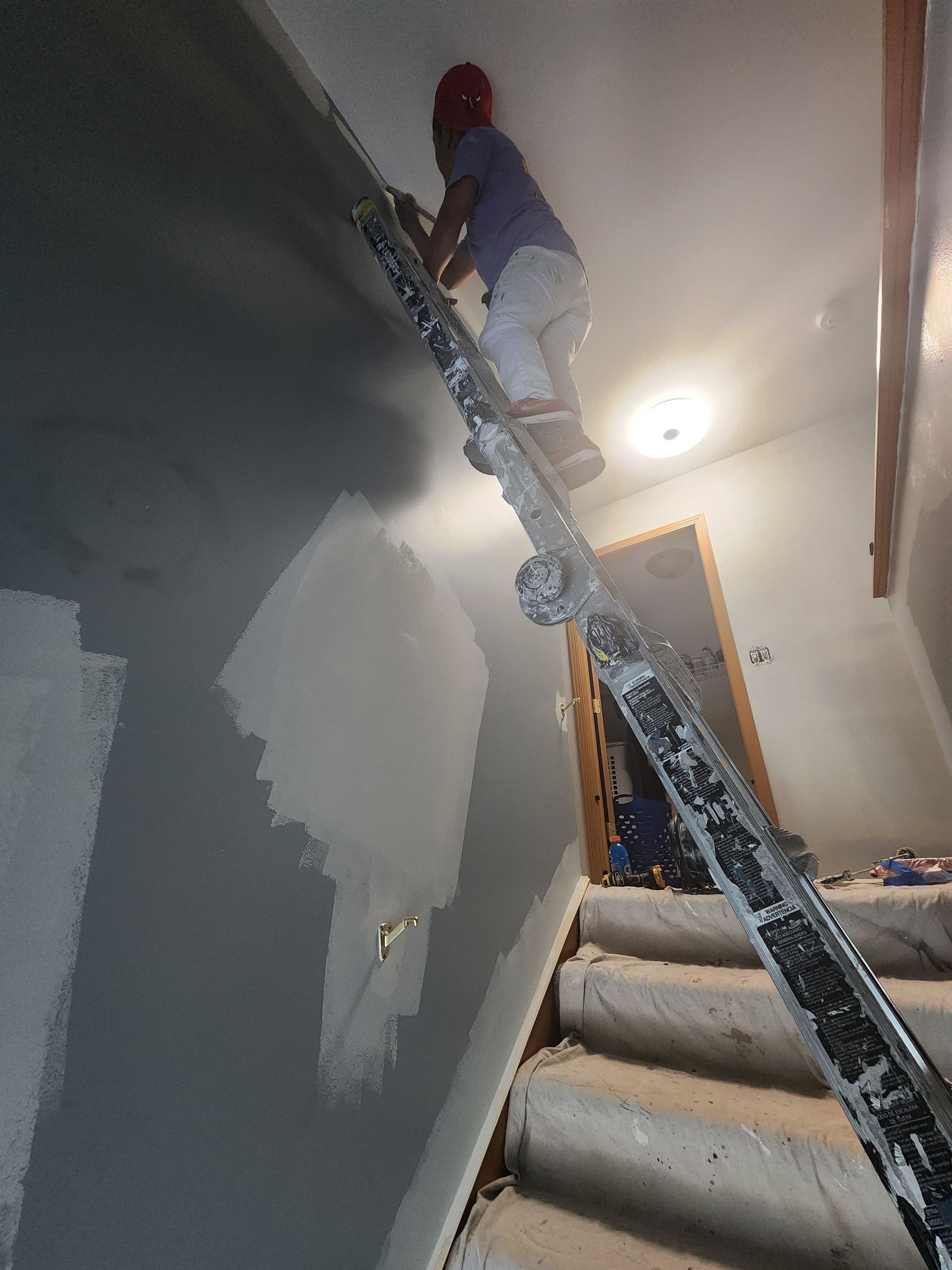 A man is standing on a ladder painting a wall.