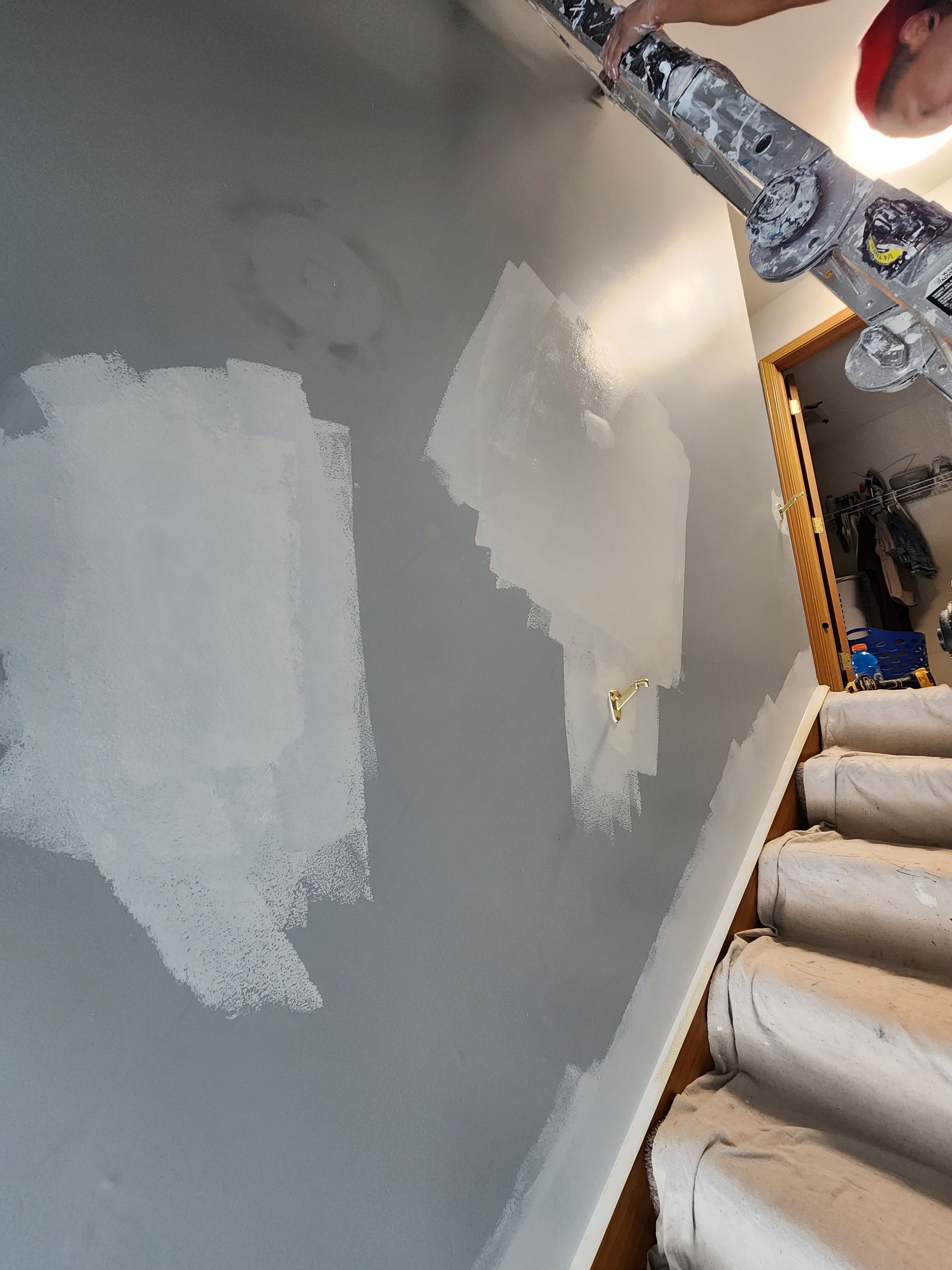 A person is painting a wall next to stairs.