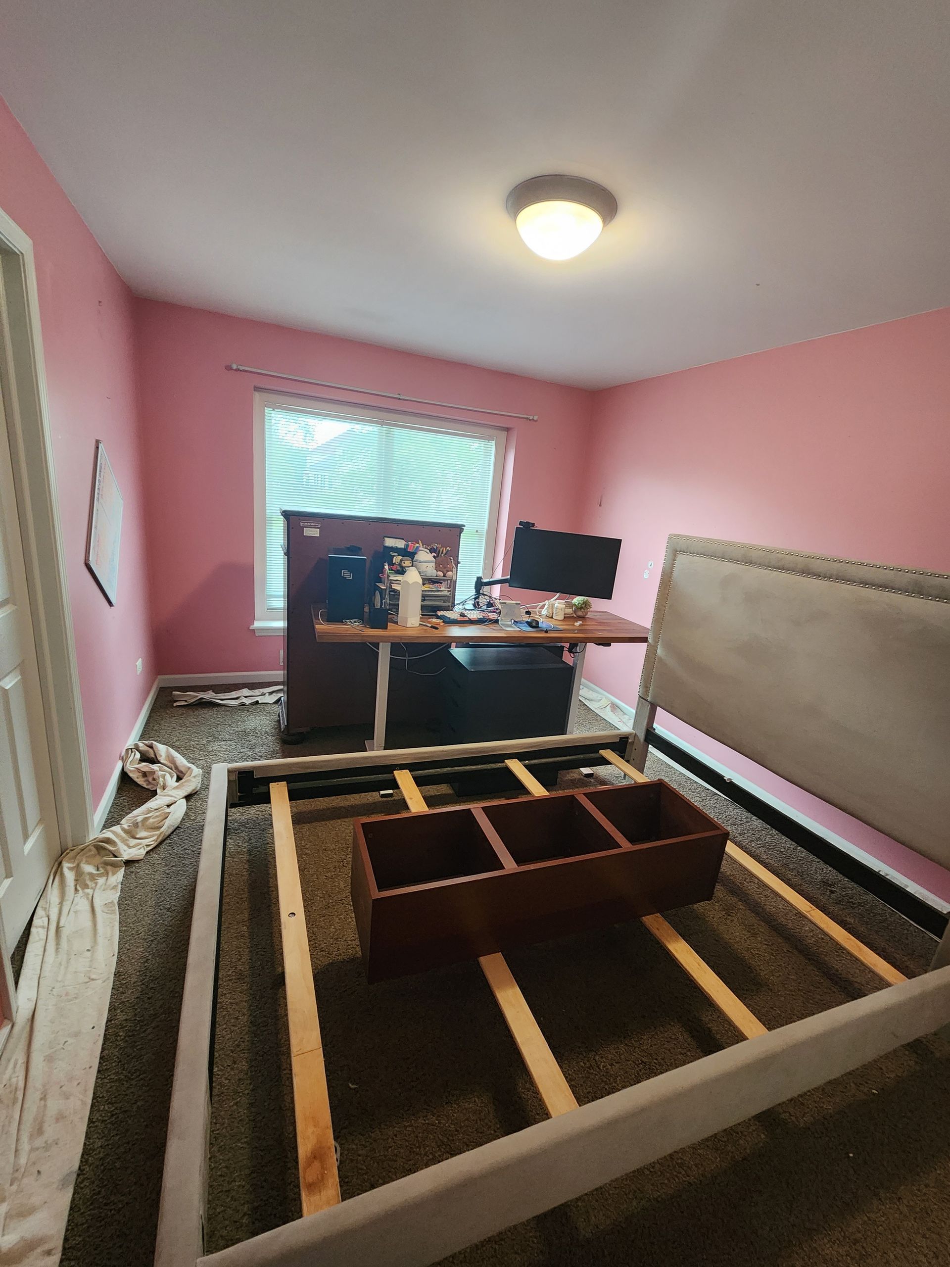 A bedroom with pink walls and a bed being built