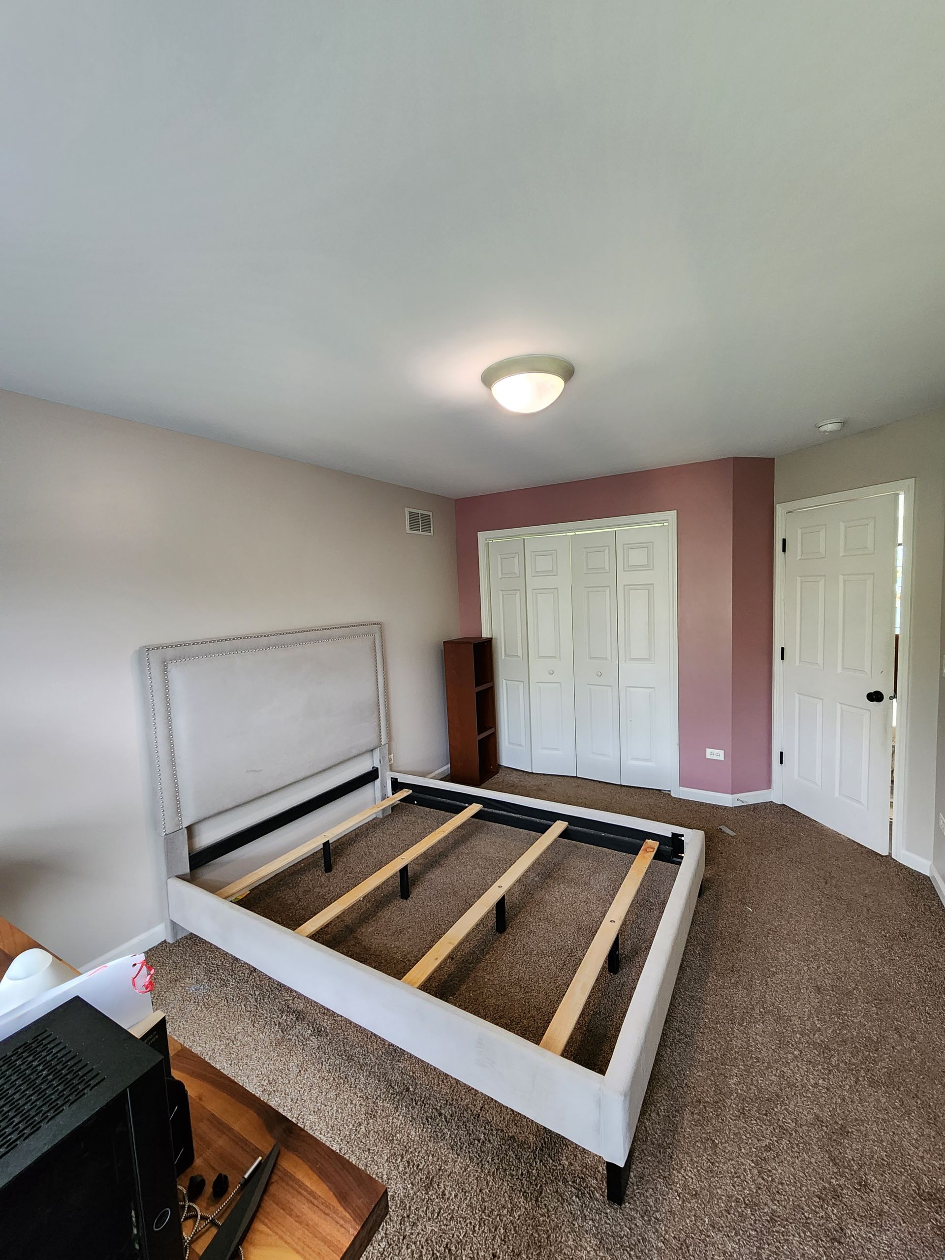 There is a bed frame in the middle of the room.