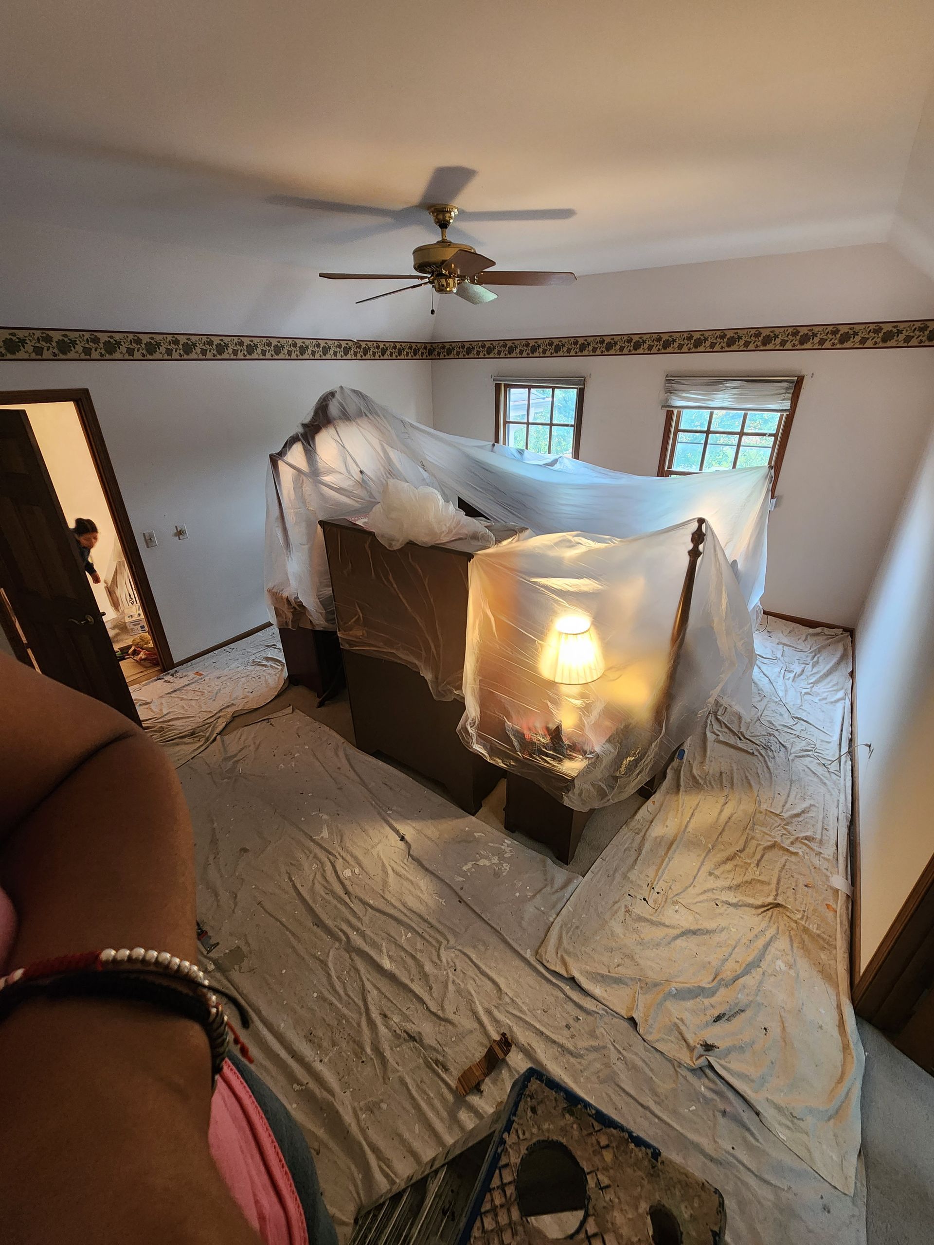 A person is standing in a room with a ceiling fan.