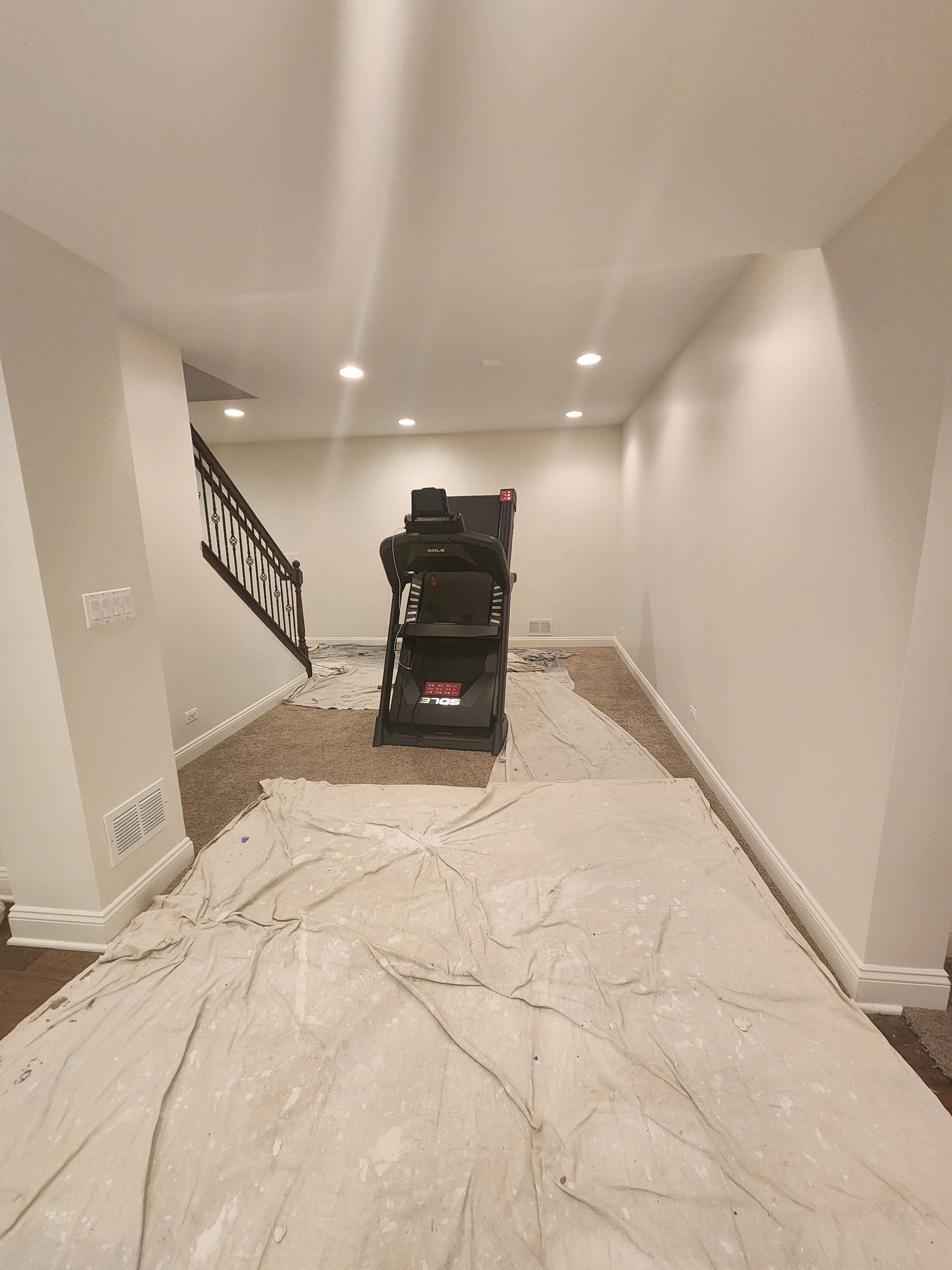 A basement with a staircase and a carpeted floor.