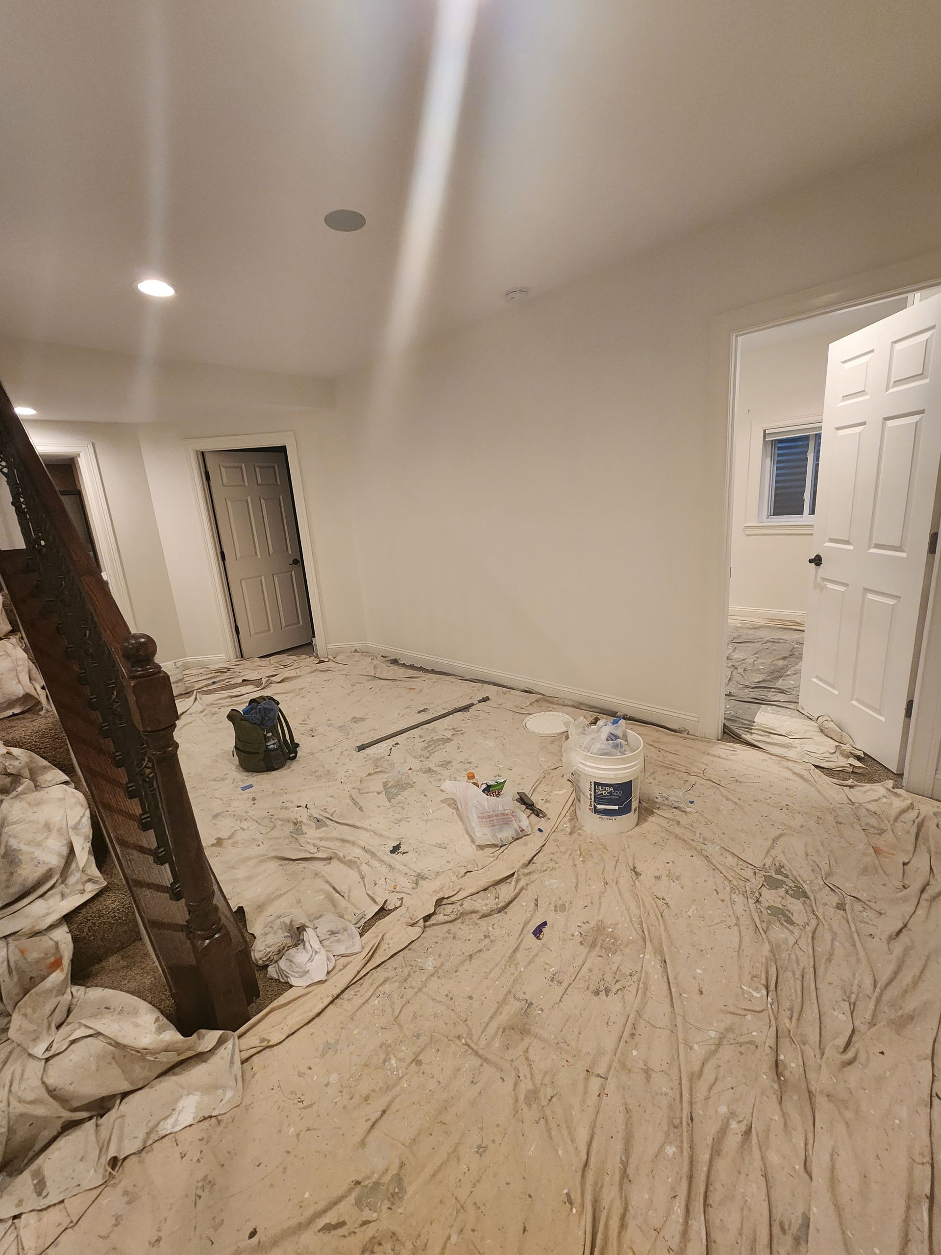 A room with white walls and a bucket of paint on the floor.
