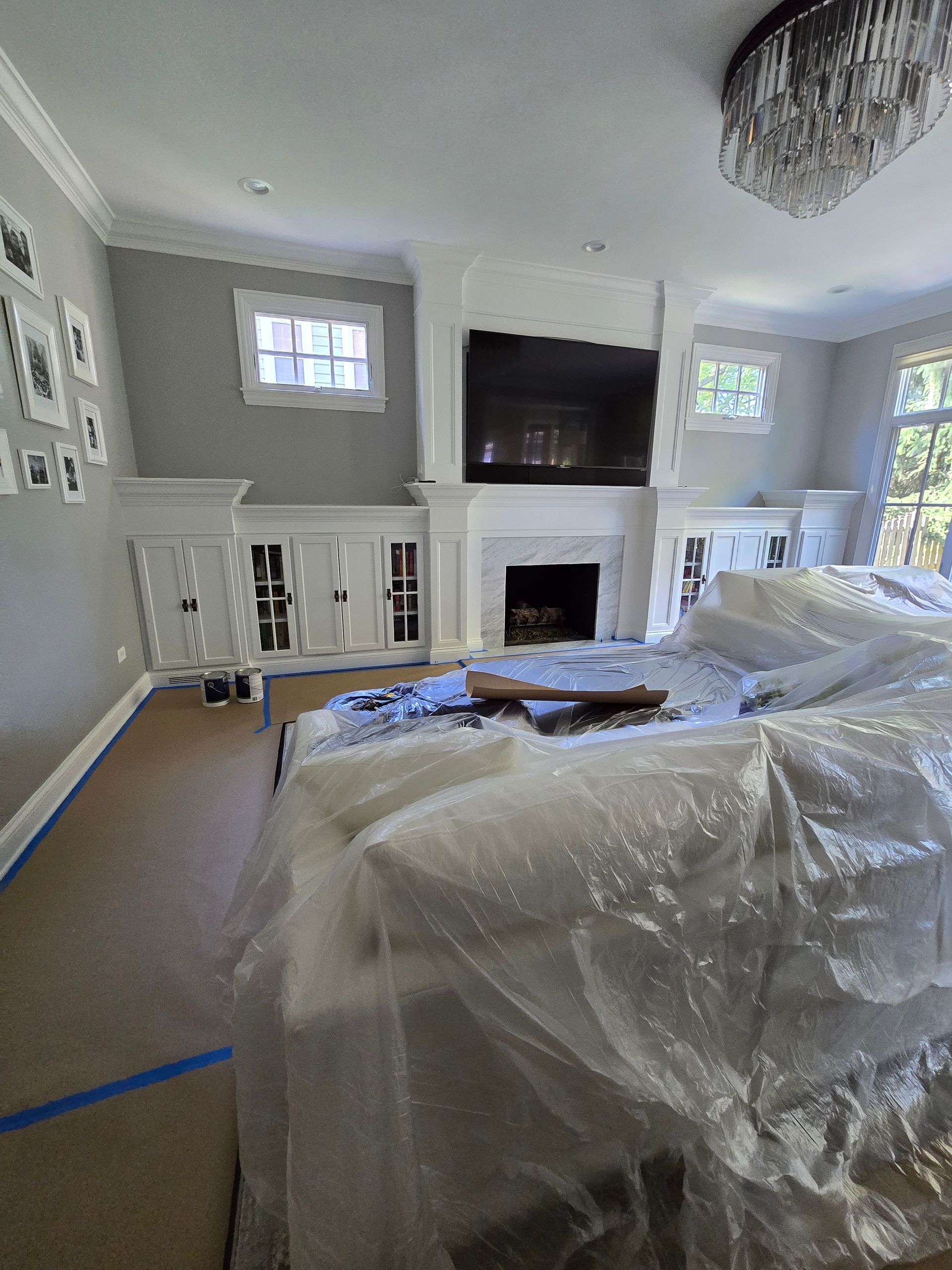 A living room with a couch covered in plastic and a fireplace.