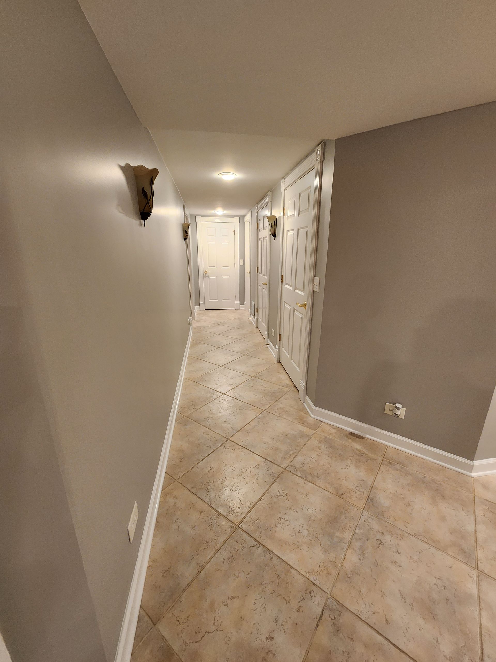 A long hallway with tile floors and gray walls in a house.