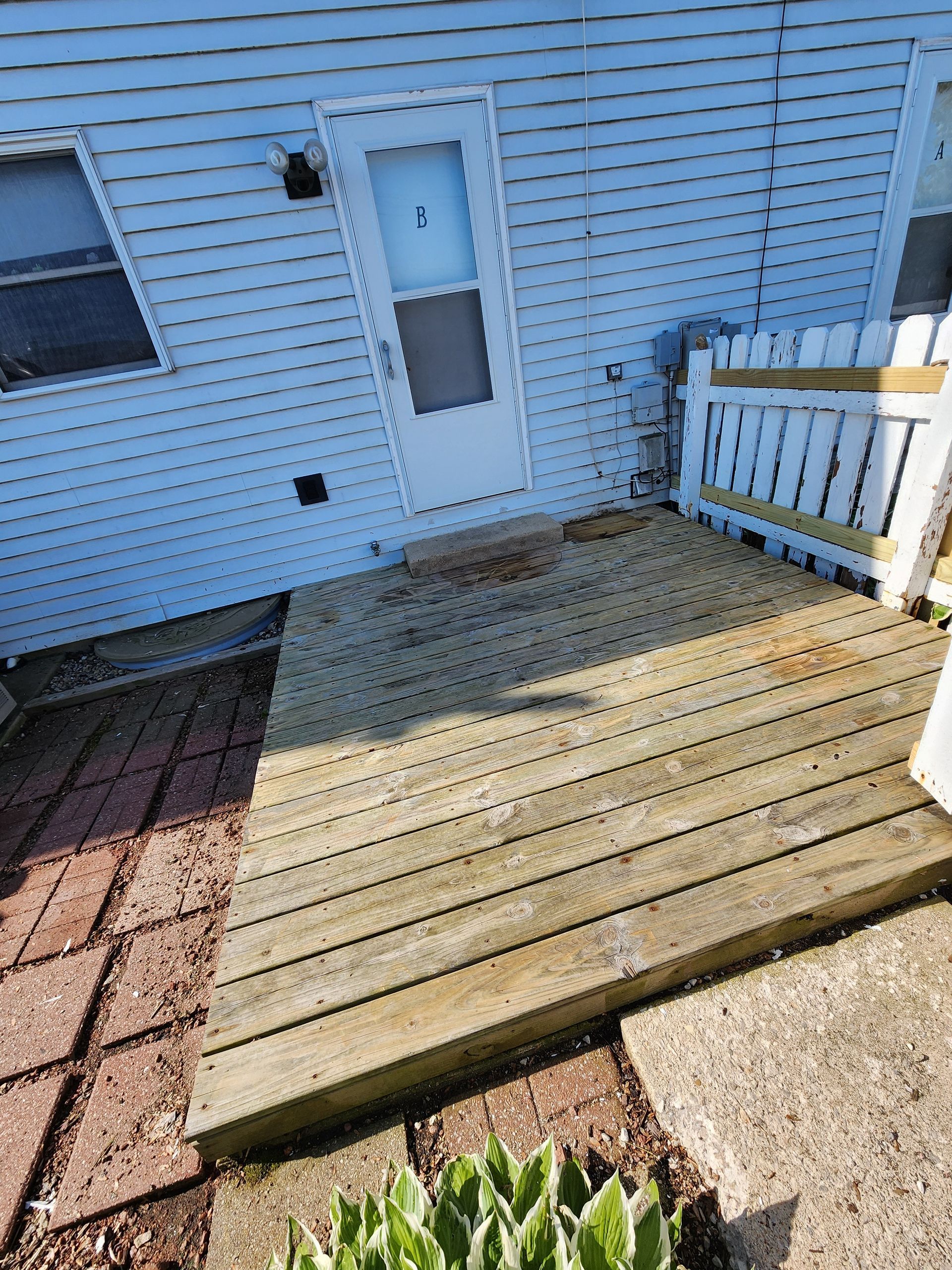 There is a wooden deck in front of a white house.