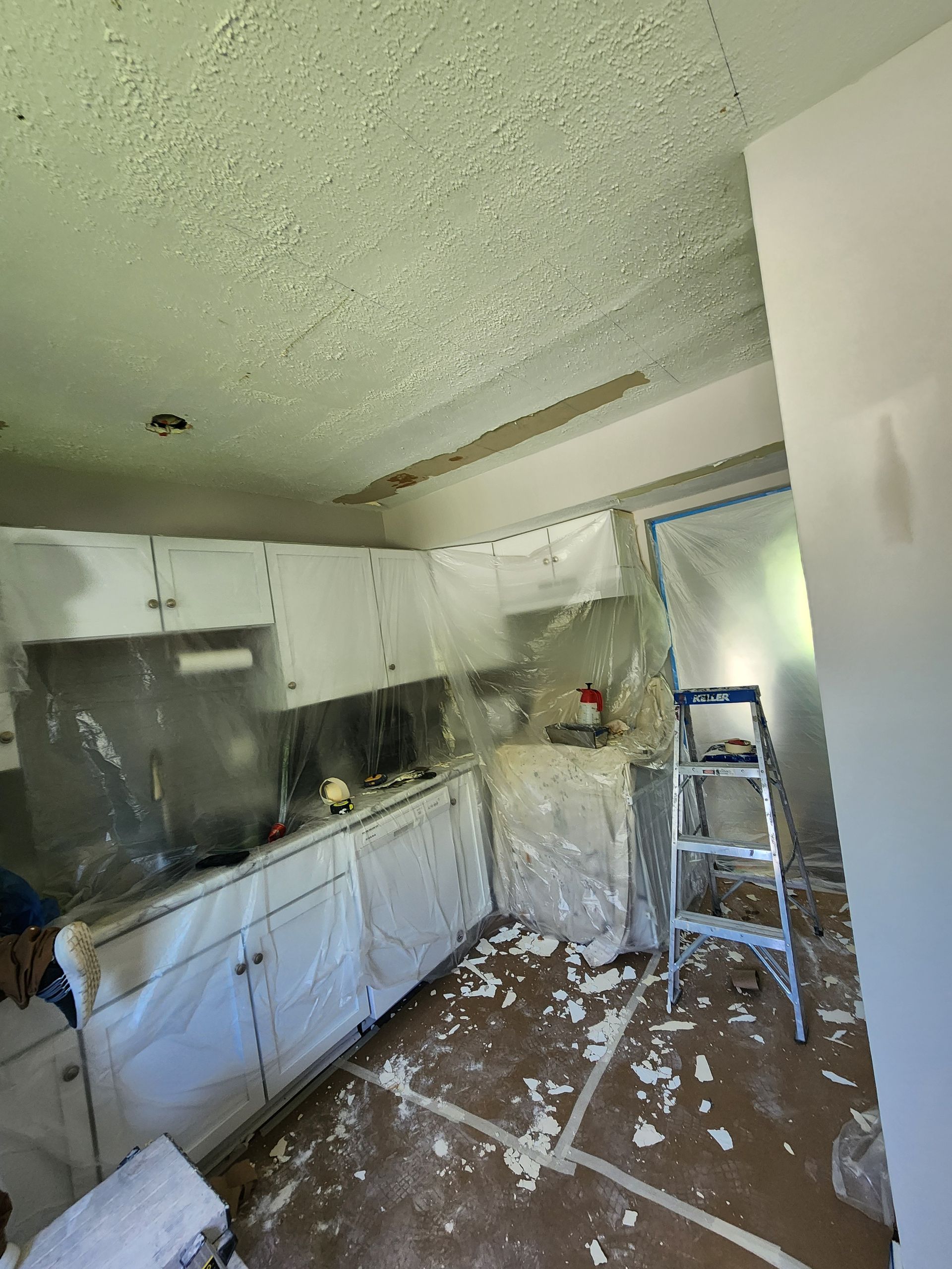 A kitchen with white cabinets and a ladder in it