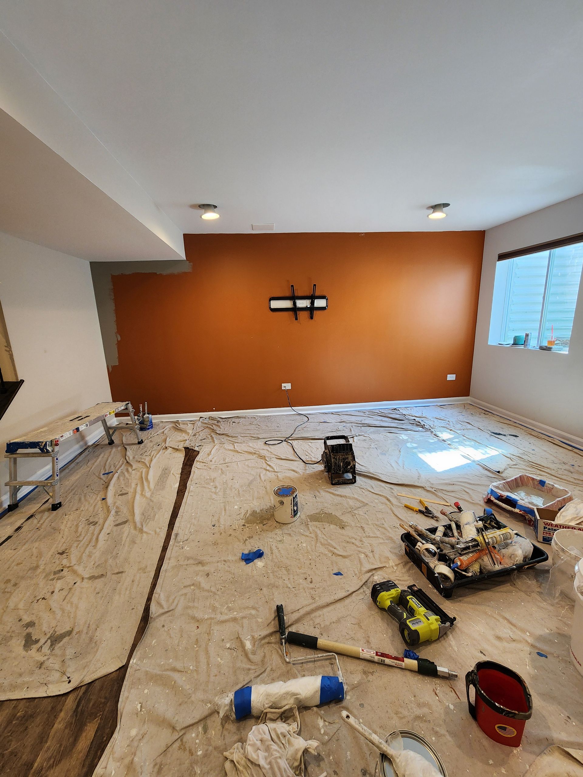 A room that is being painted with a lot of tools on the floor.