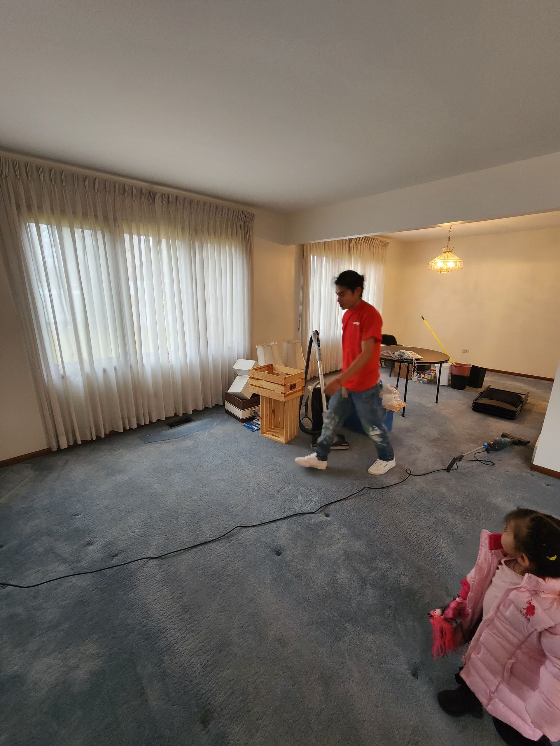 A man is standing in a living room with a vacuum cleaner.