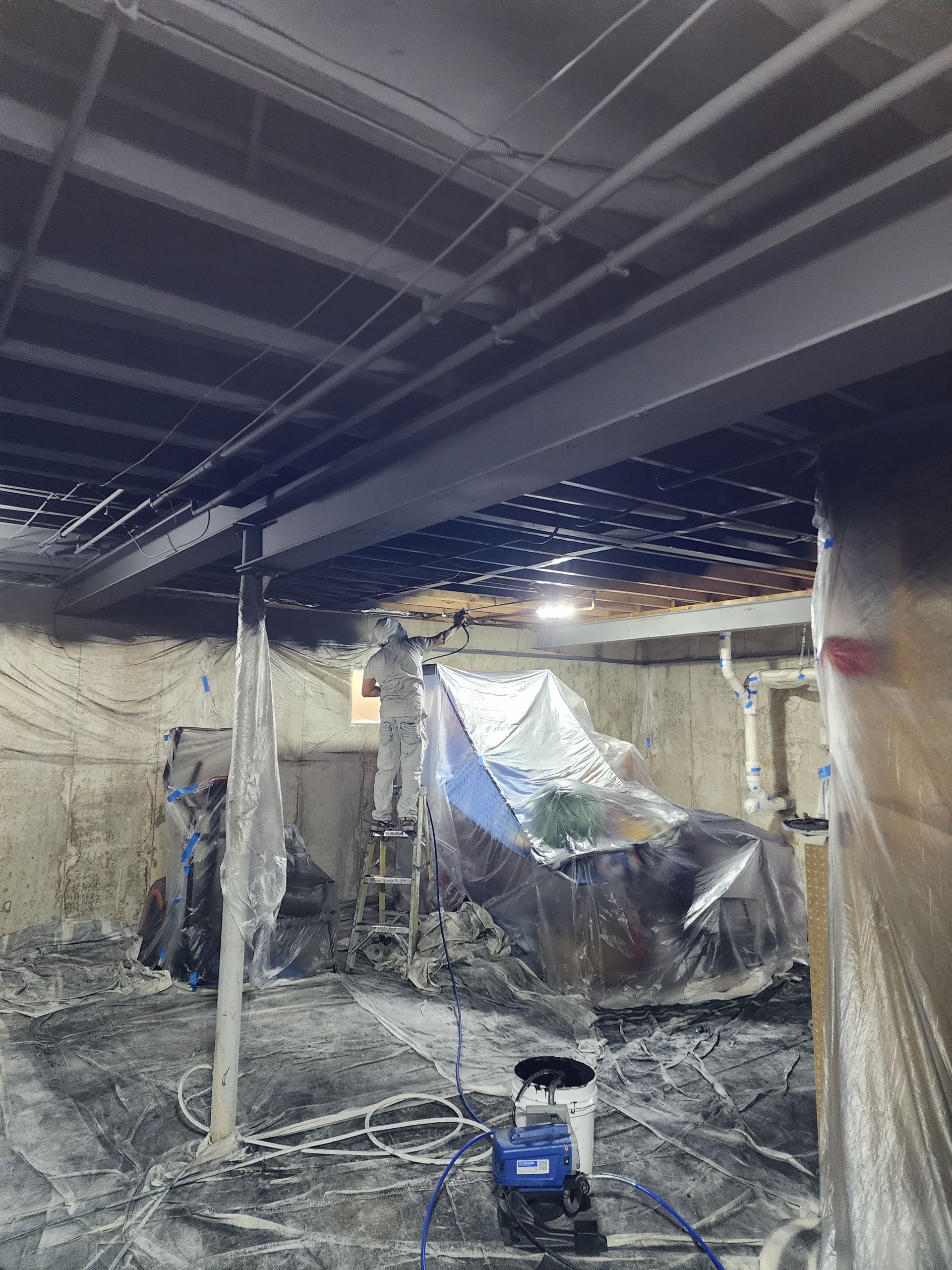 A basement under construction with a ladder and a vacuum cleaner.