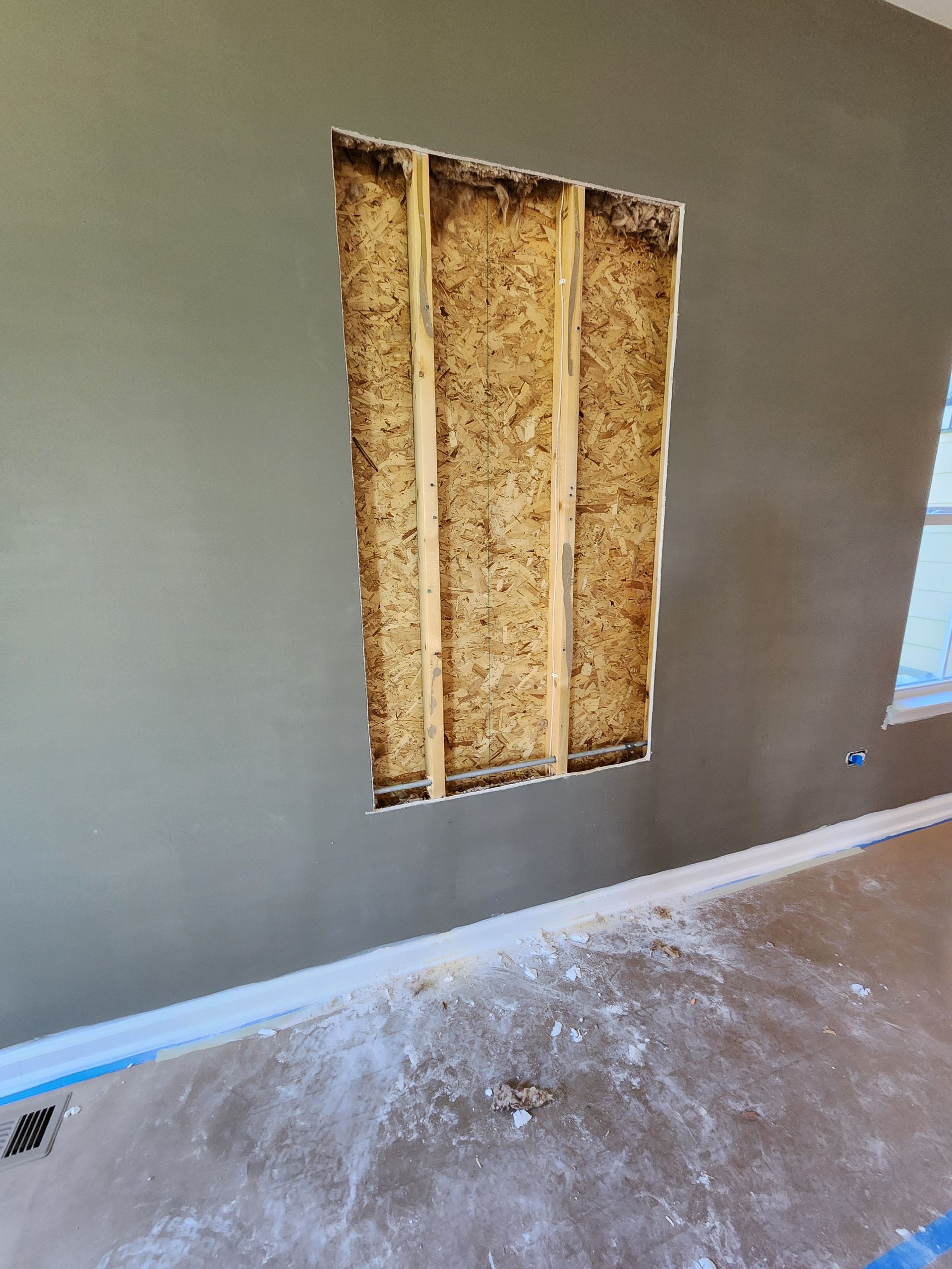 A room with a hole in the wall and a window.