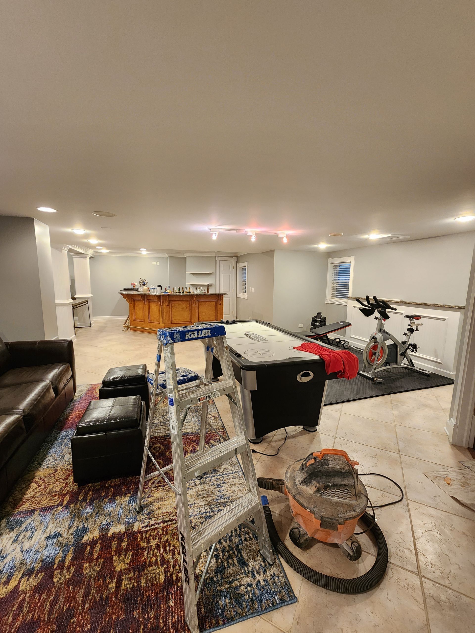 A living room with a pool table and a vacuum cleaner.