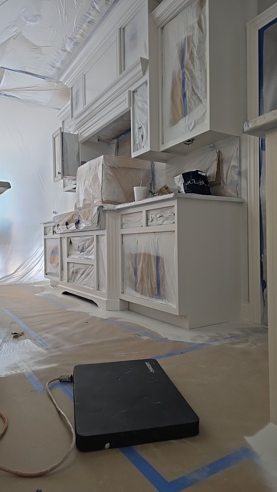 A laptop is sitting on the floor in a kitchen under construction.