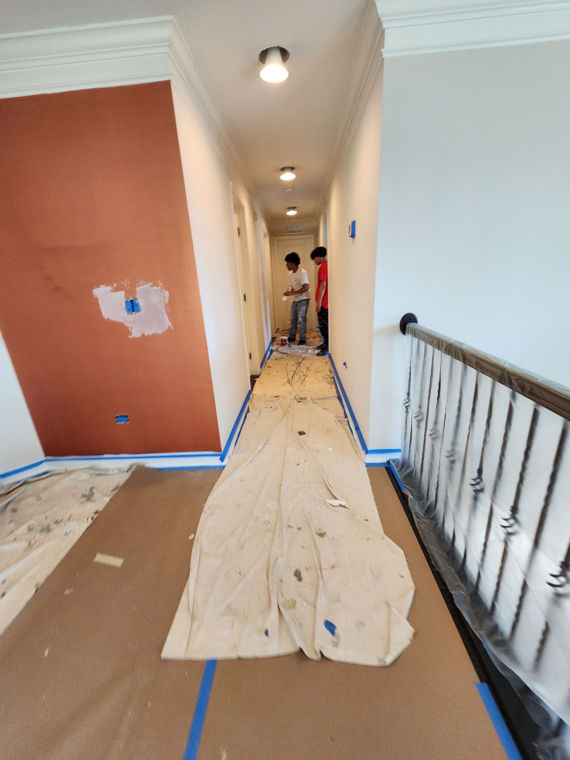 A hallway that is being painted with a blanket on the floor
