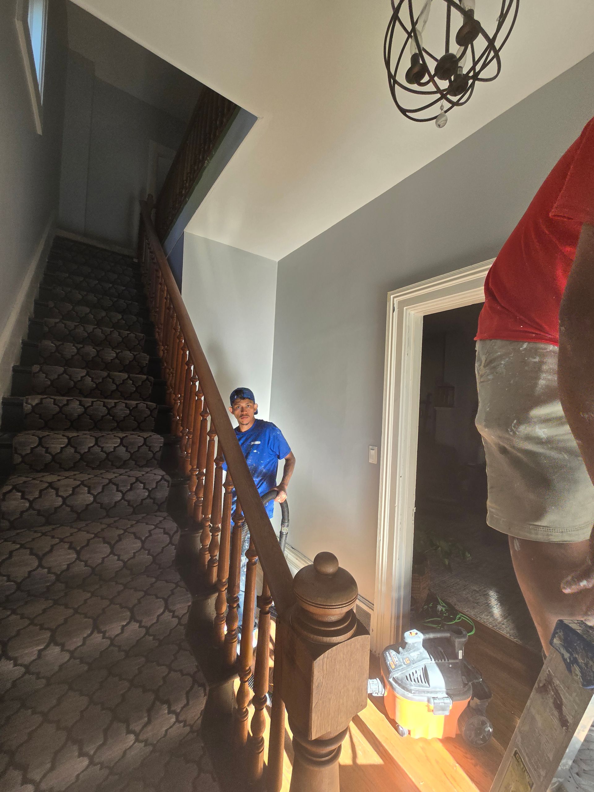 A man is standing on a wooden railing looking down a set of stairs.