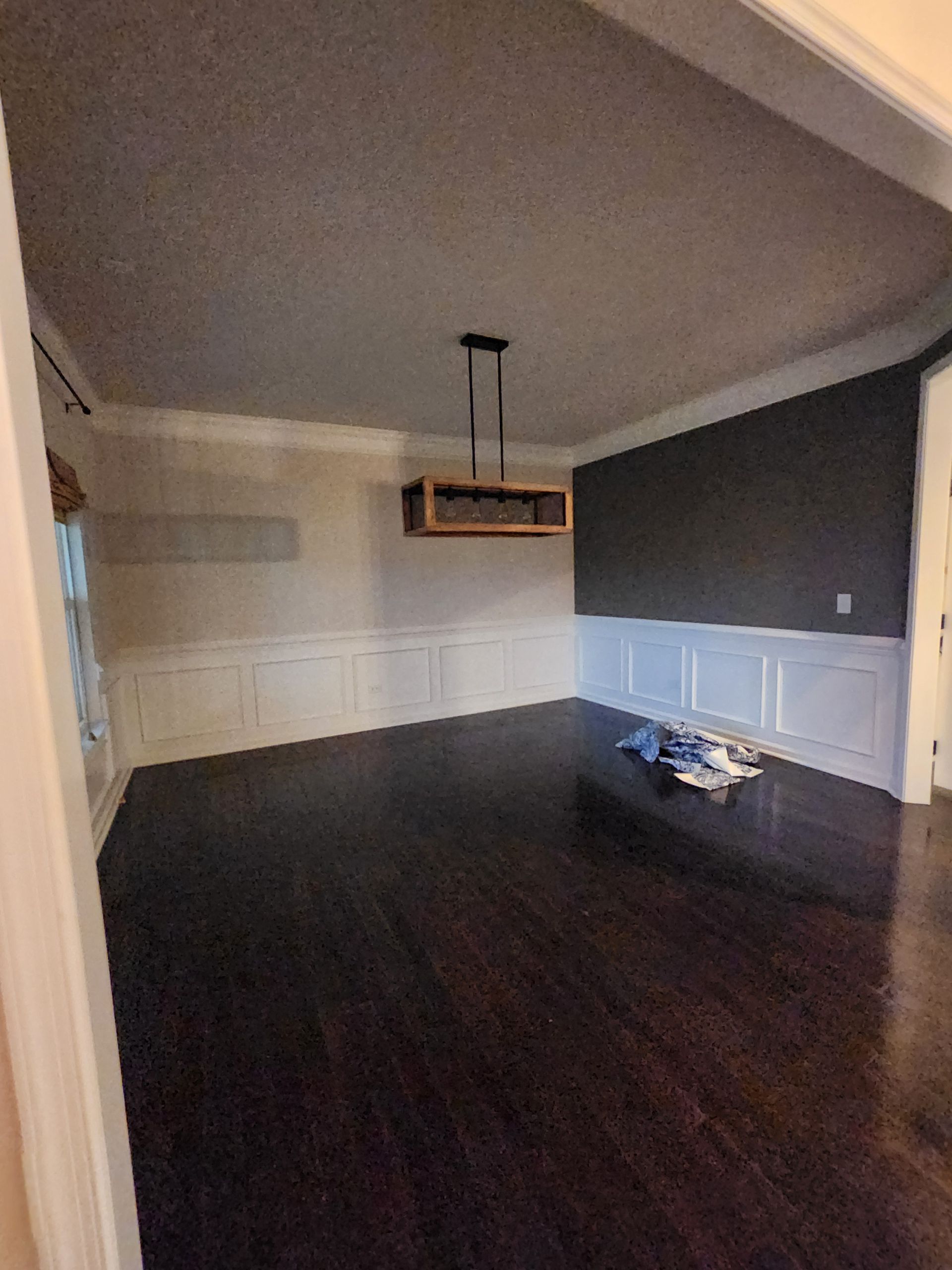 An empty dining room with hardwood floors and a chandelier hanging from the ceiling.
