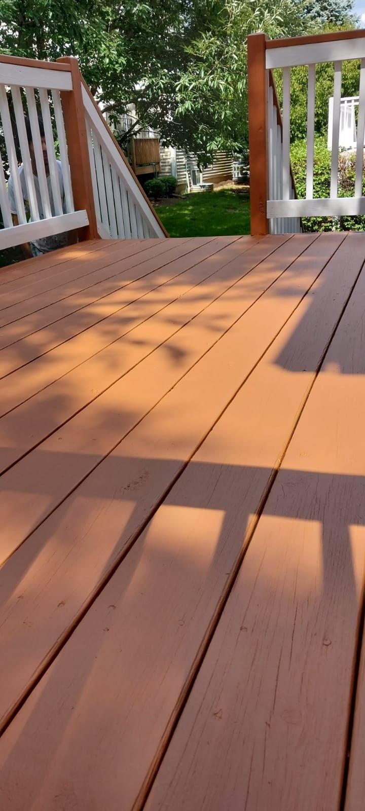 A wooden deck with a white railing and trees in the background.