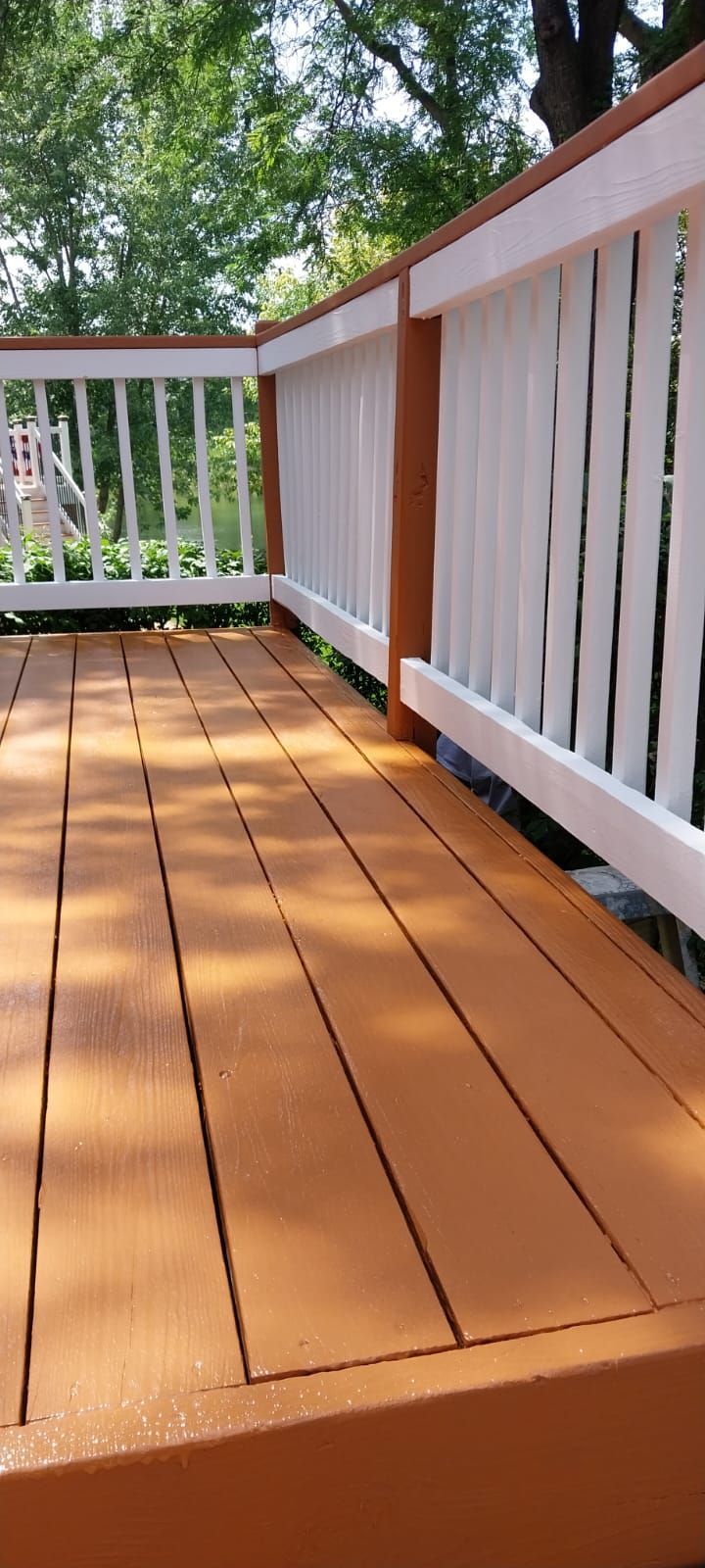 A wooden deck with a white railing and trees in the background.