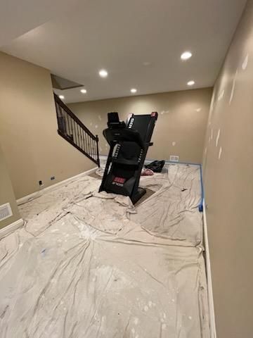 A treadmill is sitting on top of a white tarp in a basement.