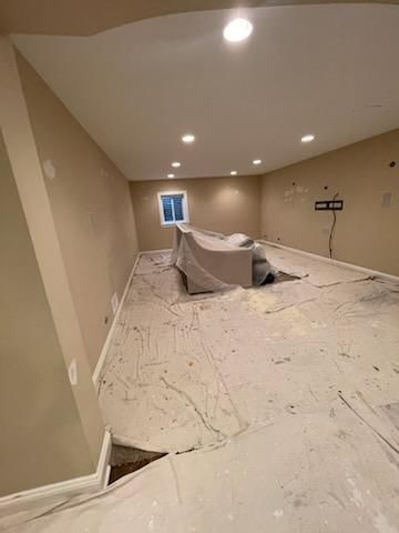 A basement is being painted and has a couch on the floor.