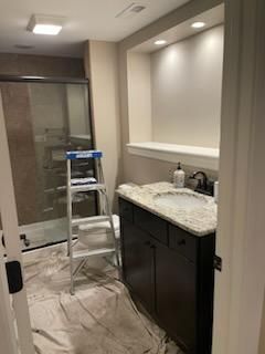 A bathroom with a sink , toilet , shower and ladder.