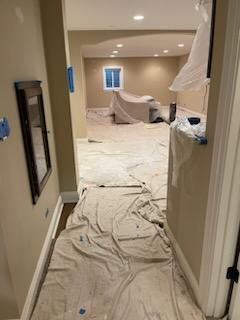 A hallway with a white tarp on the floor and a mirror.