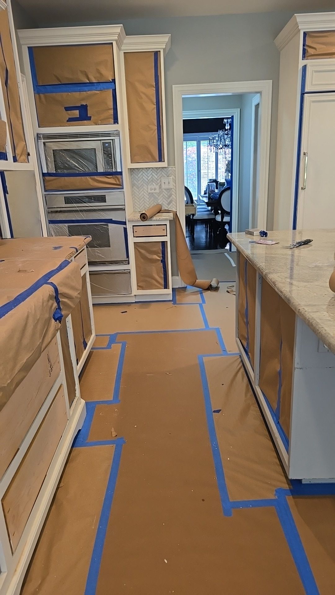 A kitchen is being painted and covered in blue tape.