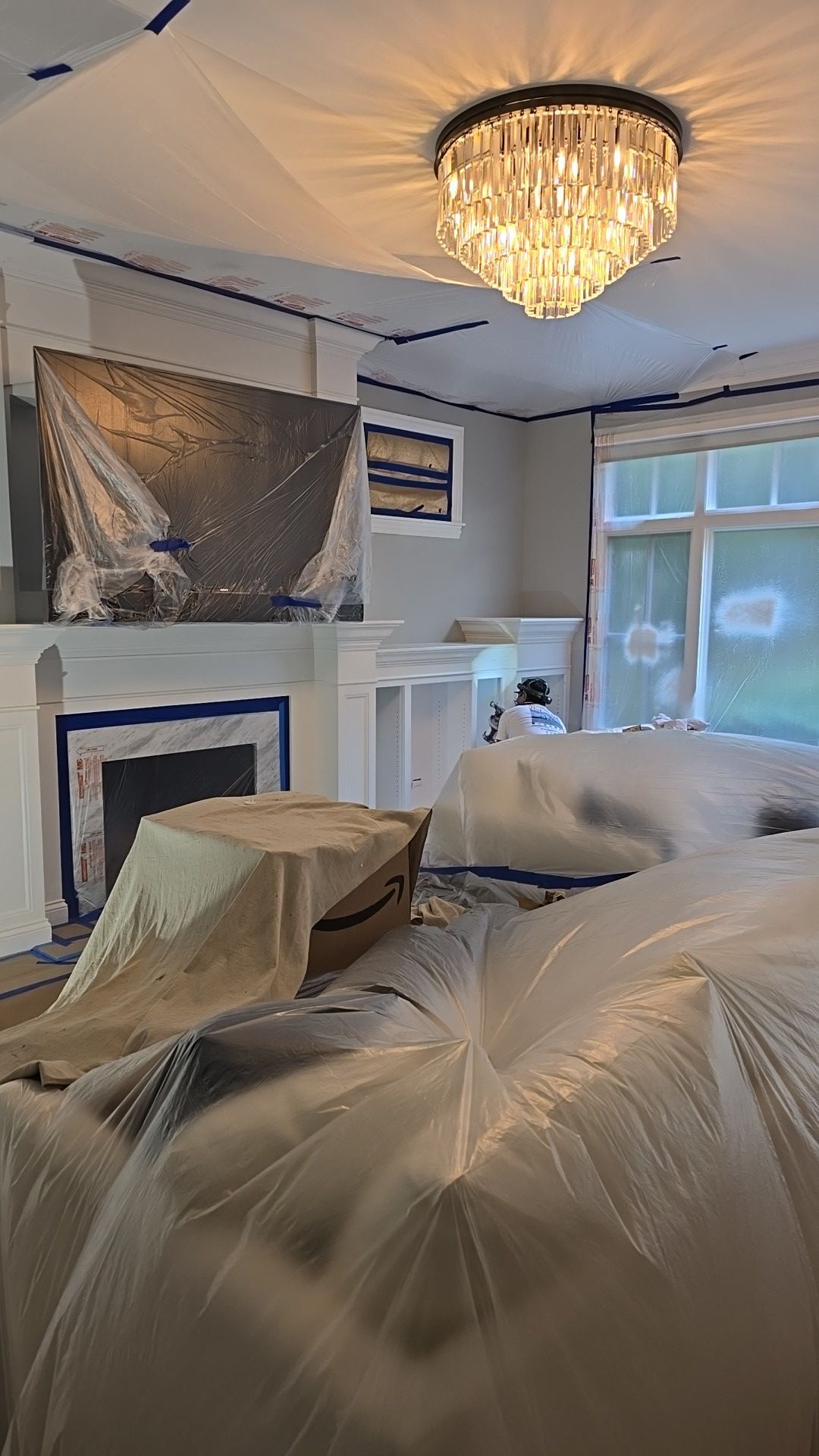 A living room with a fireplace and a chandelier covered in plastic.