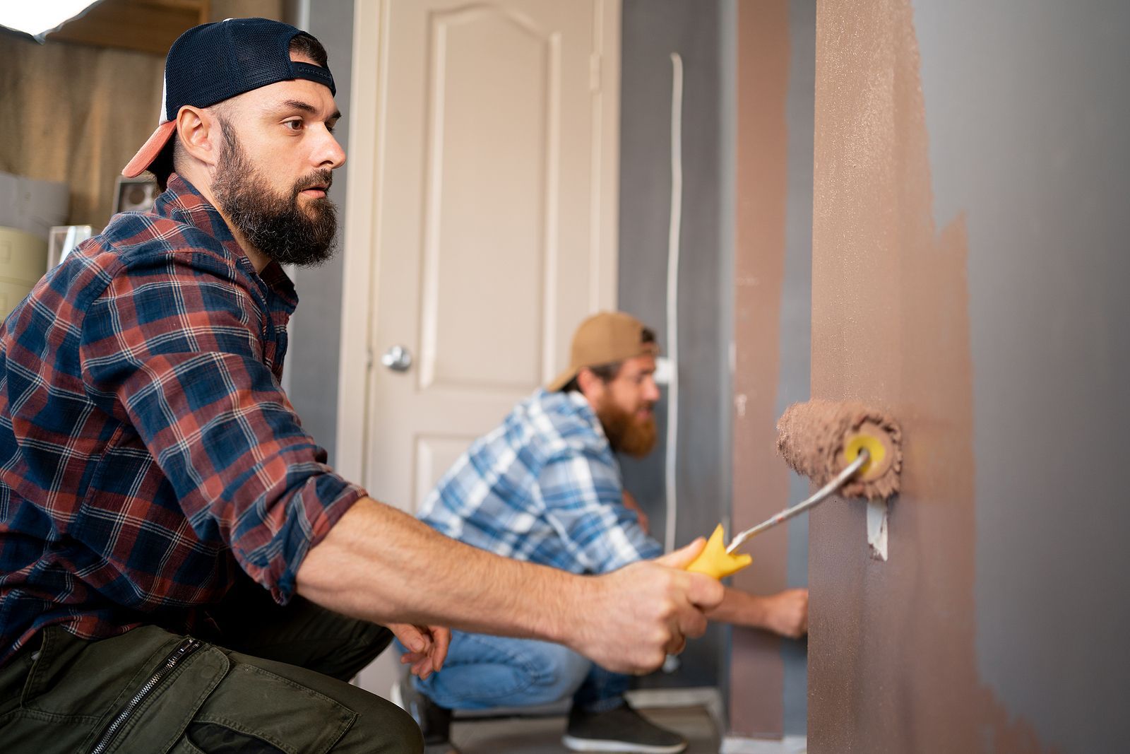 two men painting interior wall of house