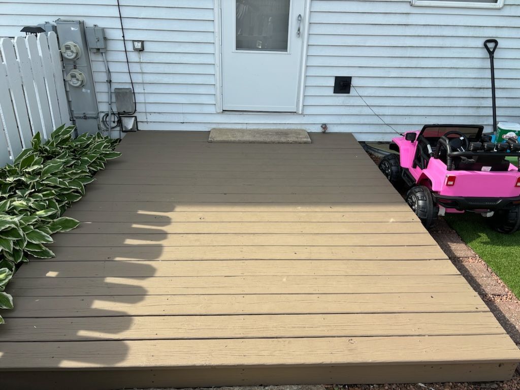 A pink jeep is parked on a wooden deck in front of a house.